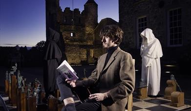 Beckett Festival - image of young man reading Beckett verse by the Isle of Enniskillen Beckett Chess set.