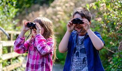 Two children looking through binoculars.