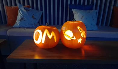 Two pumpkins craved, one with OM and the other with a planet and rocket