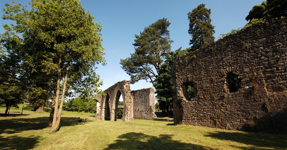 The historic stone Palace Arch in Armagh's Palace Demesne Public Park, surrounded by green trees and grass.