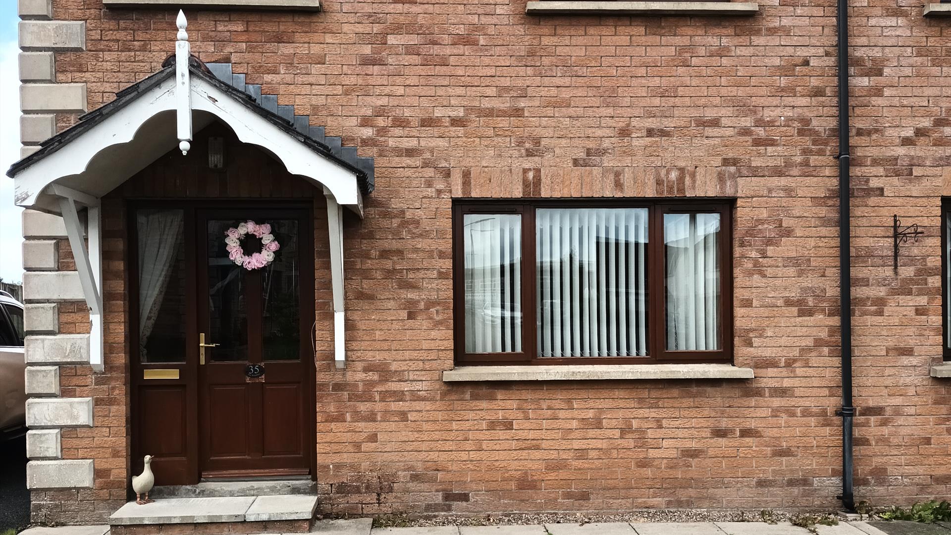 Front exterior of a semi-detached house with a small front lawn.
