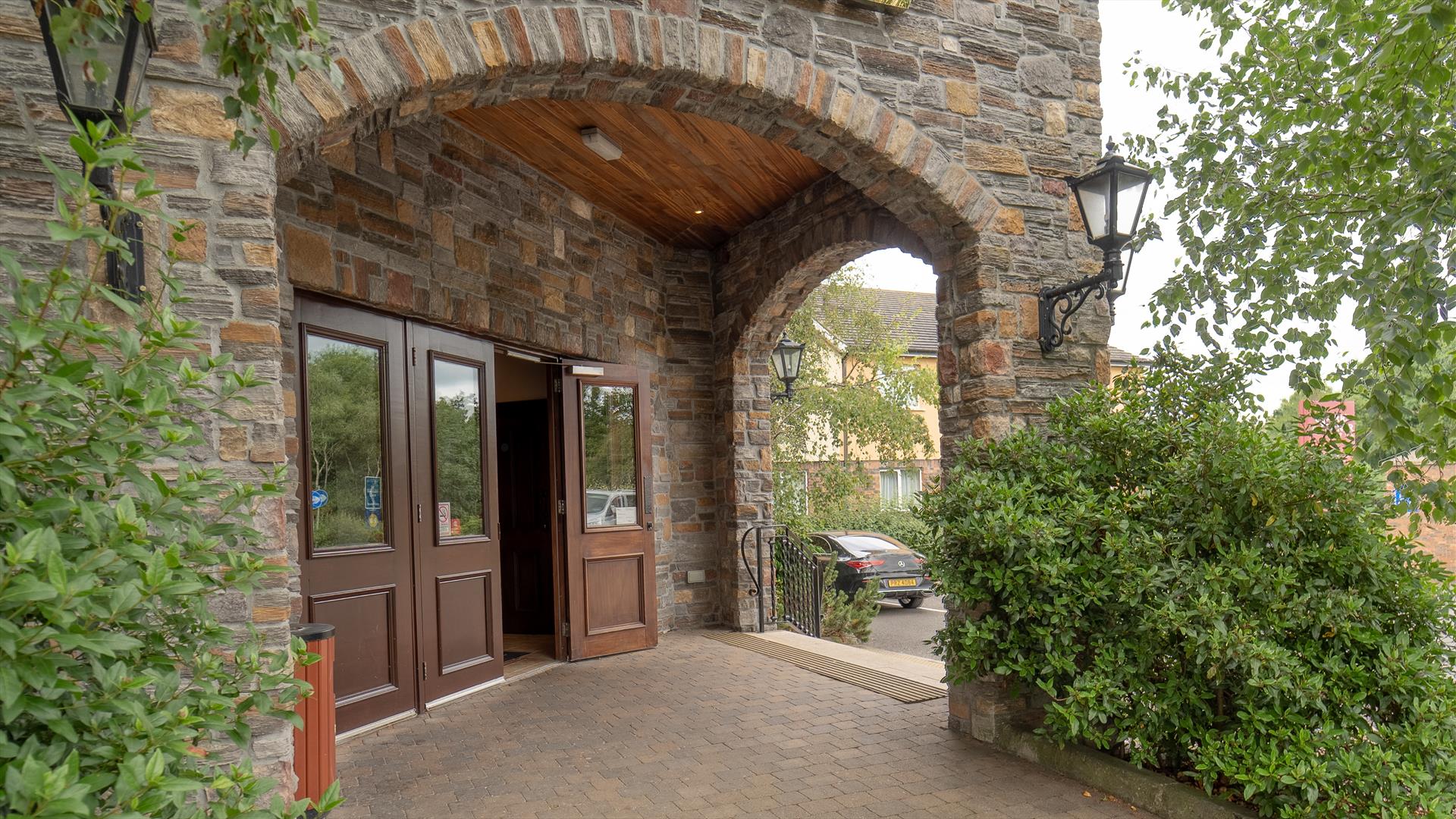 Hotel entrance under stone arches with an exit to a car park.