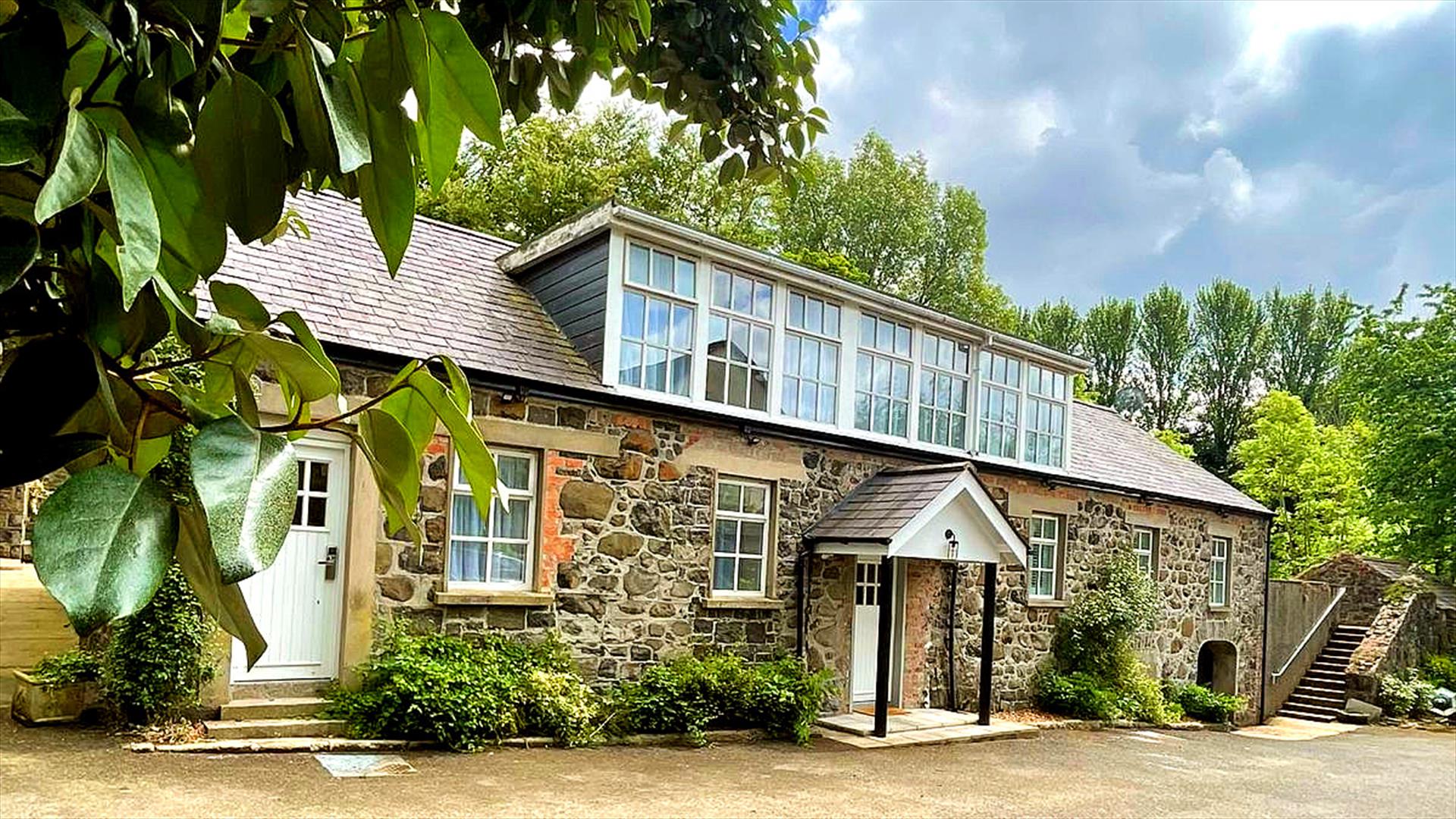 A renovated stone cottage with second floor windows.