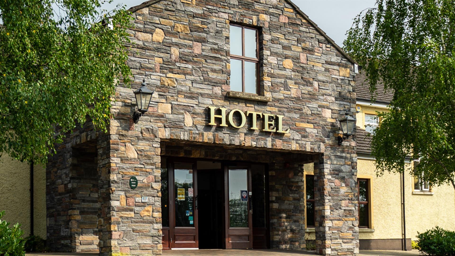 A stone entrance to a hotel with a window and trees.