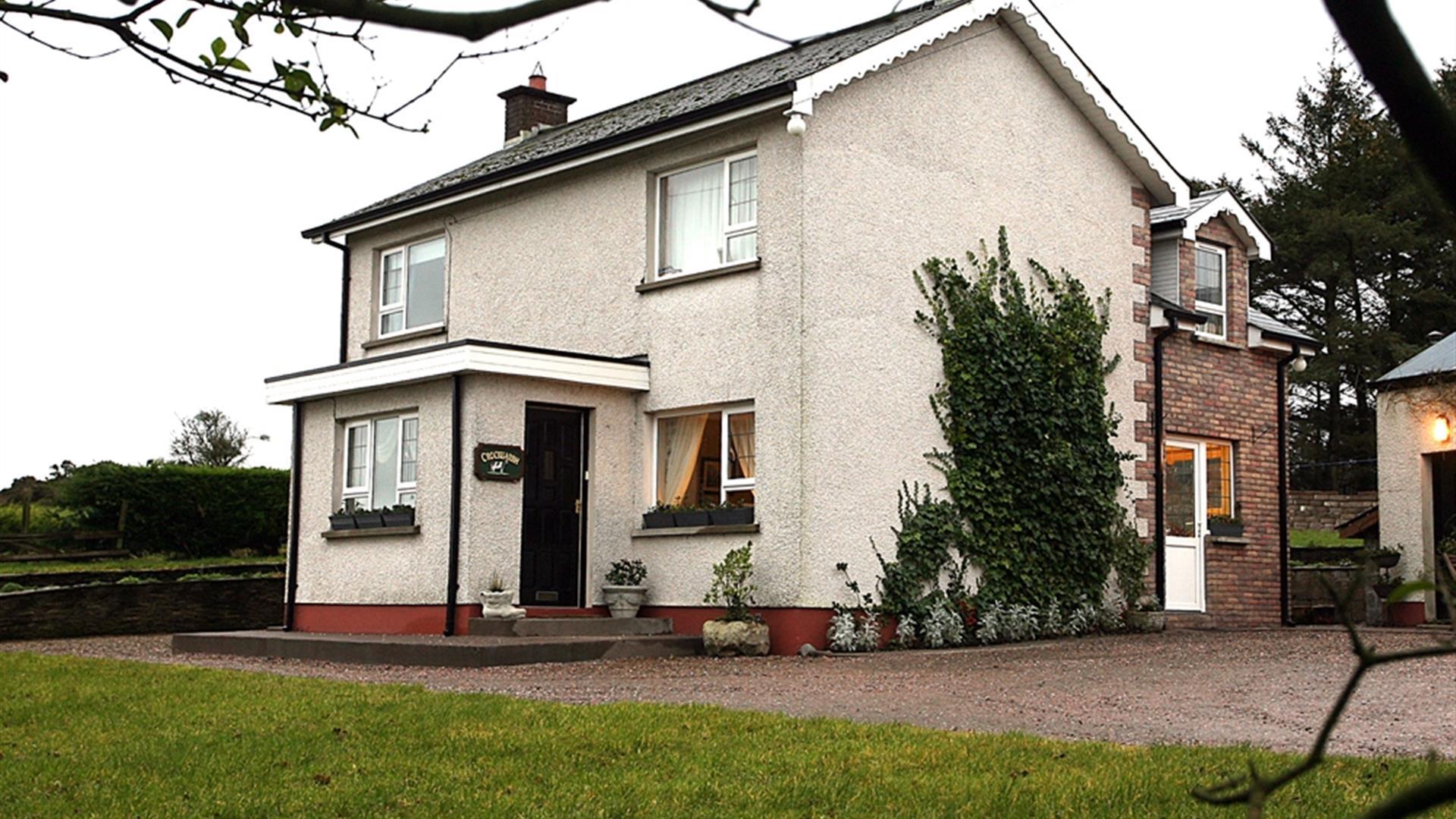 Image of a white two story house with climbing vines up the side