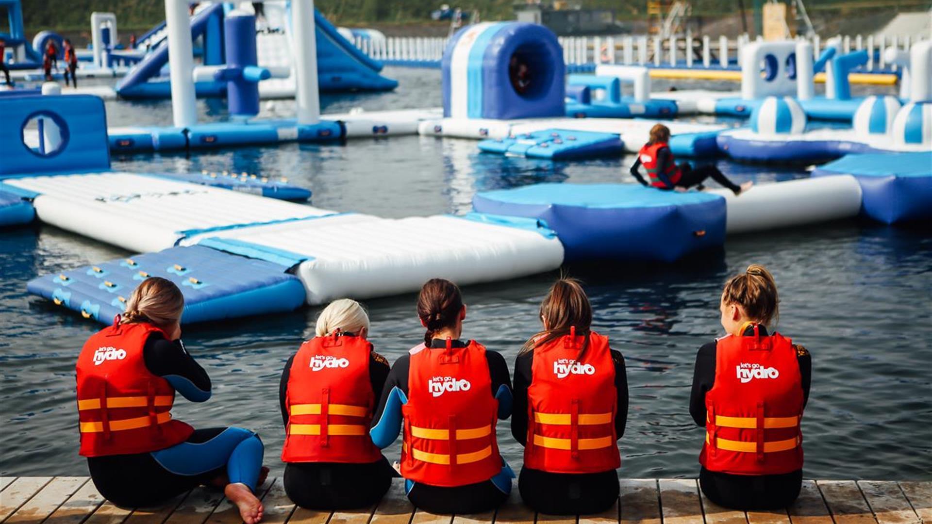 Image shows children wearing life jackets, sitting on the edge of the lake