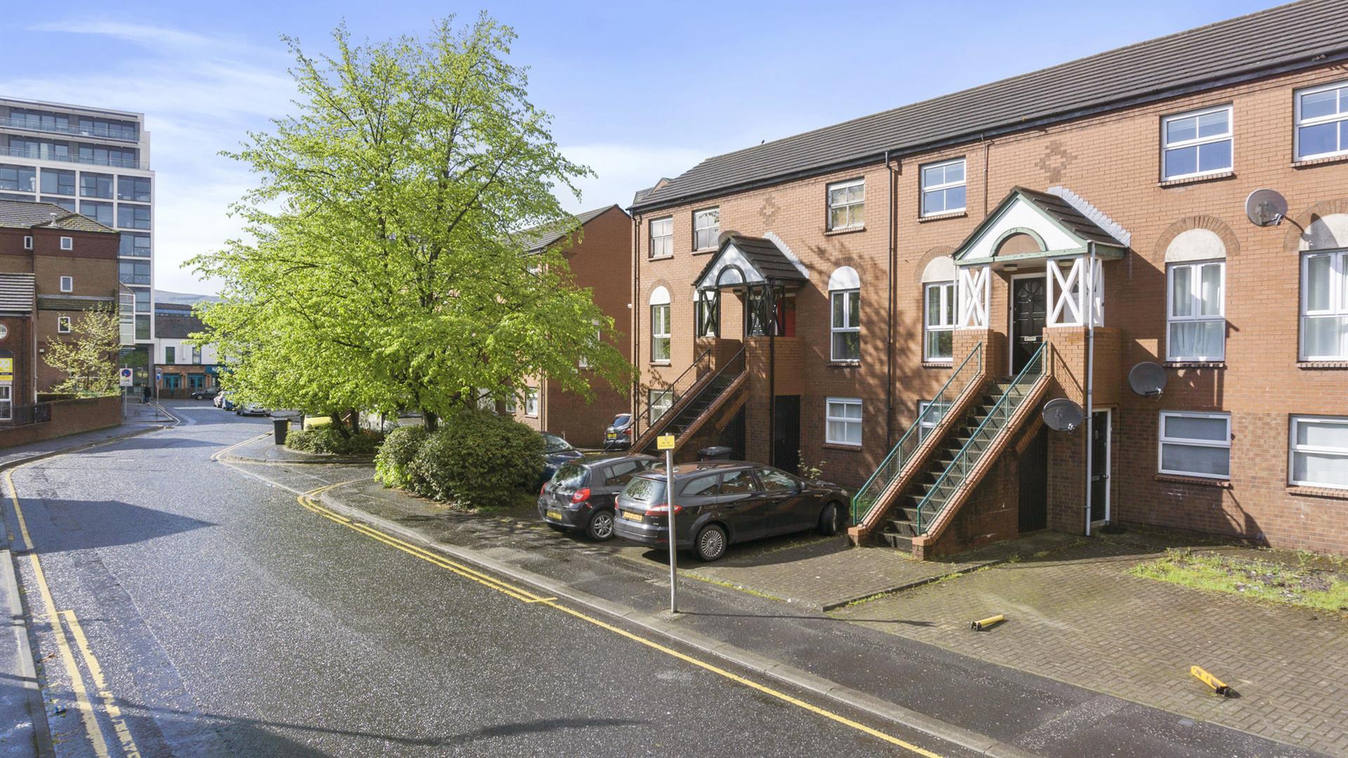 A city apartment complex with outdoor stairs leading to first floor apartments.