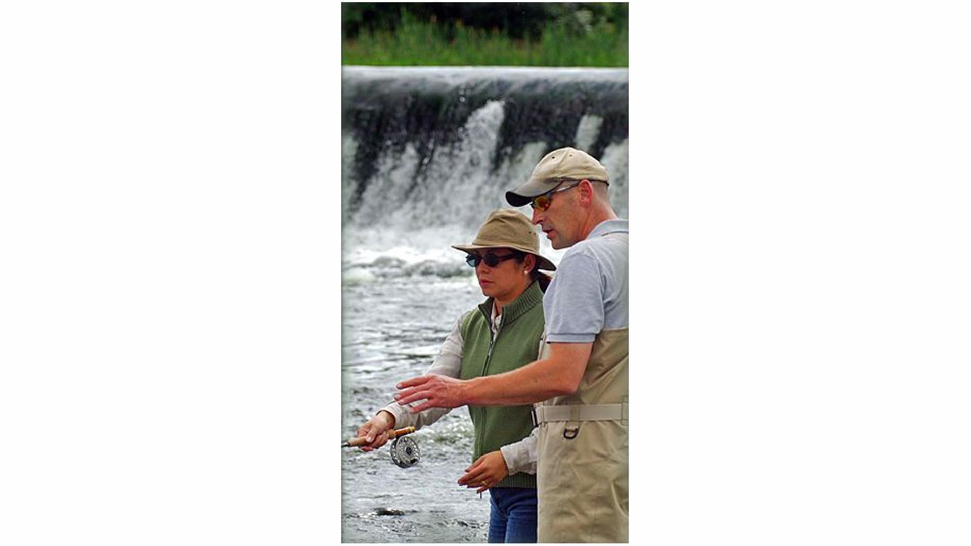 Image is of man showing woman how to fish