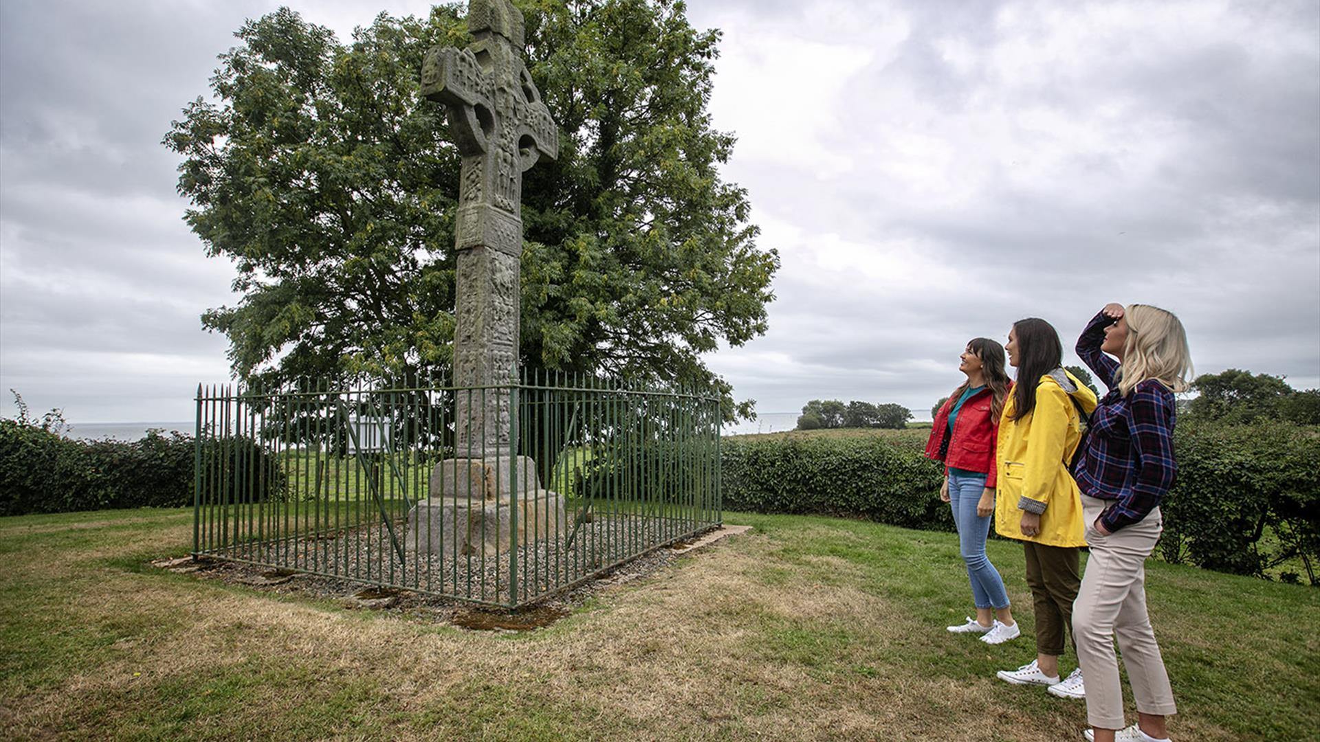 Three ladies looking up at Ardboe High cross