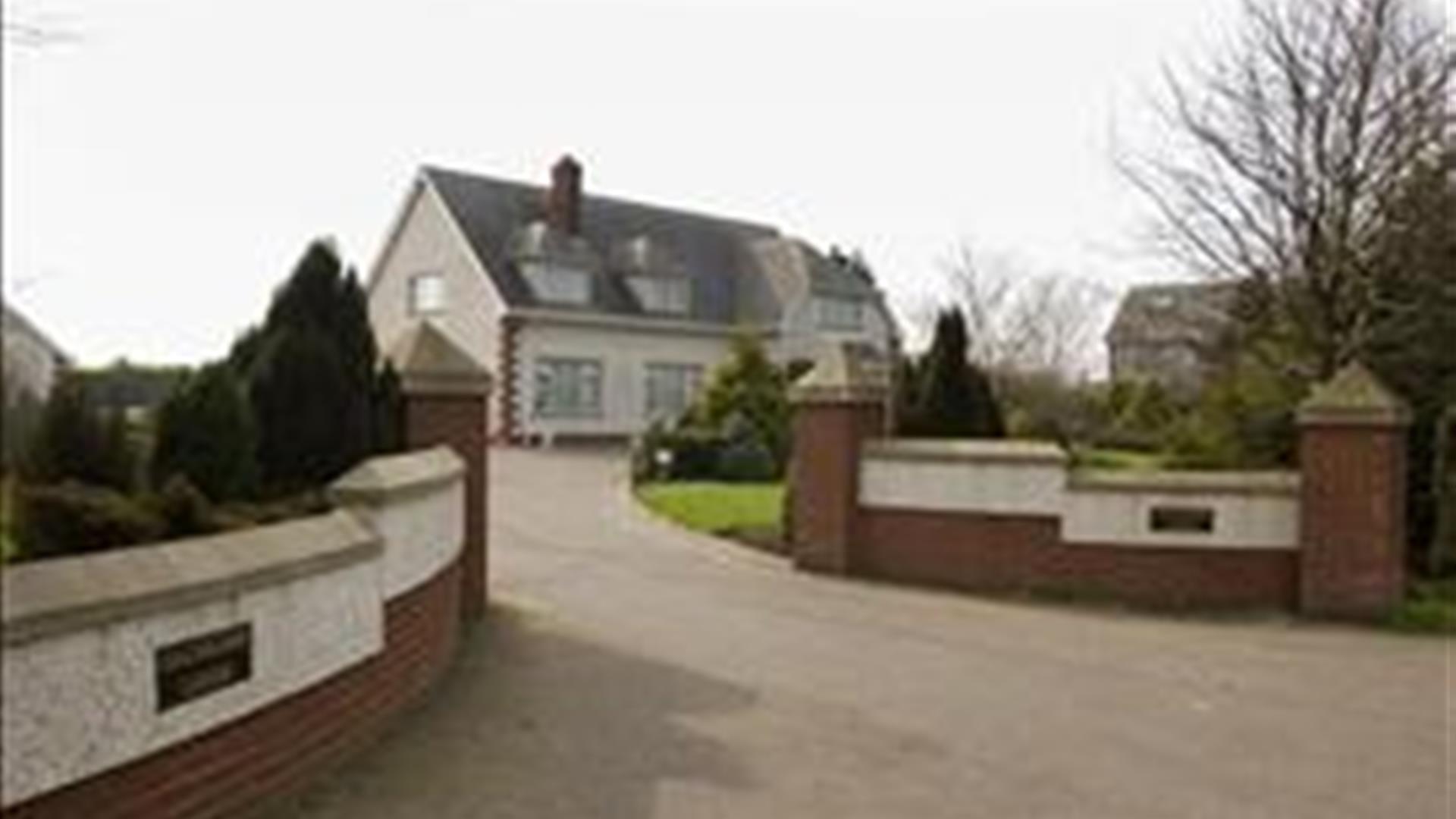 Walled driveway leading to a large lodge.