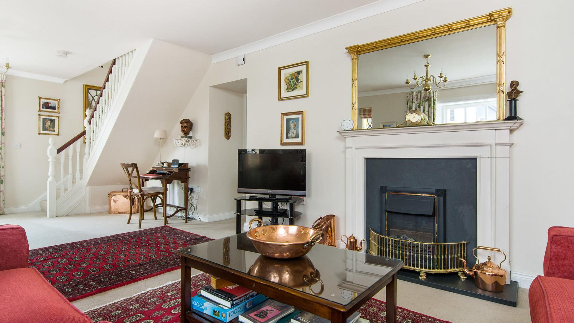 Living room with a coffee table, fireplace, TV, desk and a staircase.