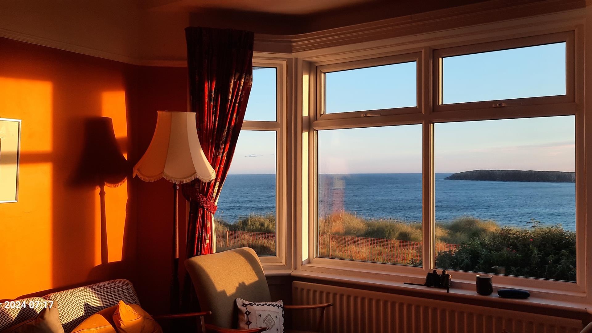Looking through the front room bay window at a sea view, early in the morning.