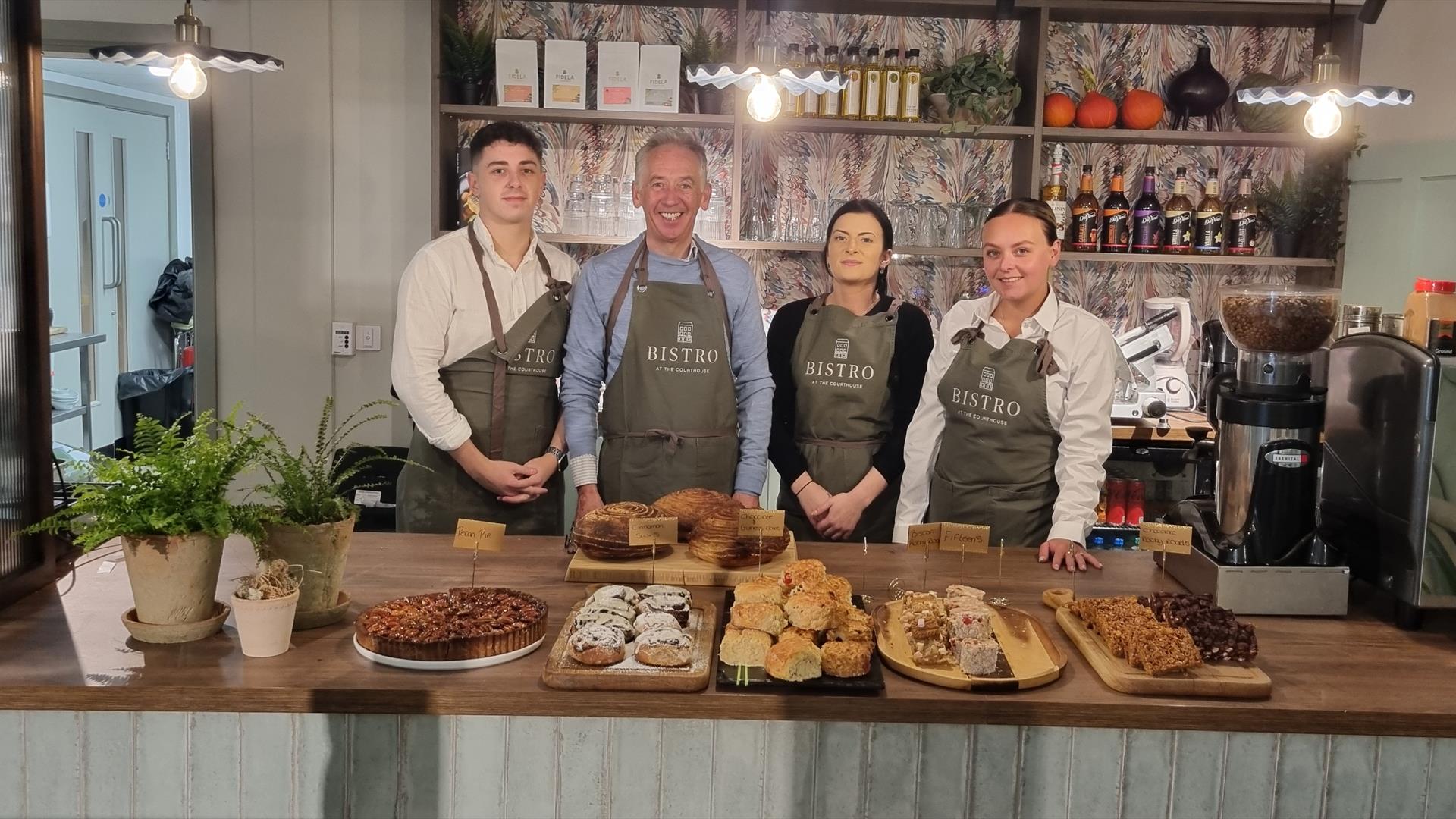 Staff from Bistro at the Courthouse stand behind the restaurants counter, with plenty of bakes and sweet treats in front of them