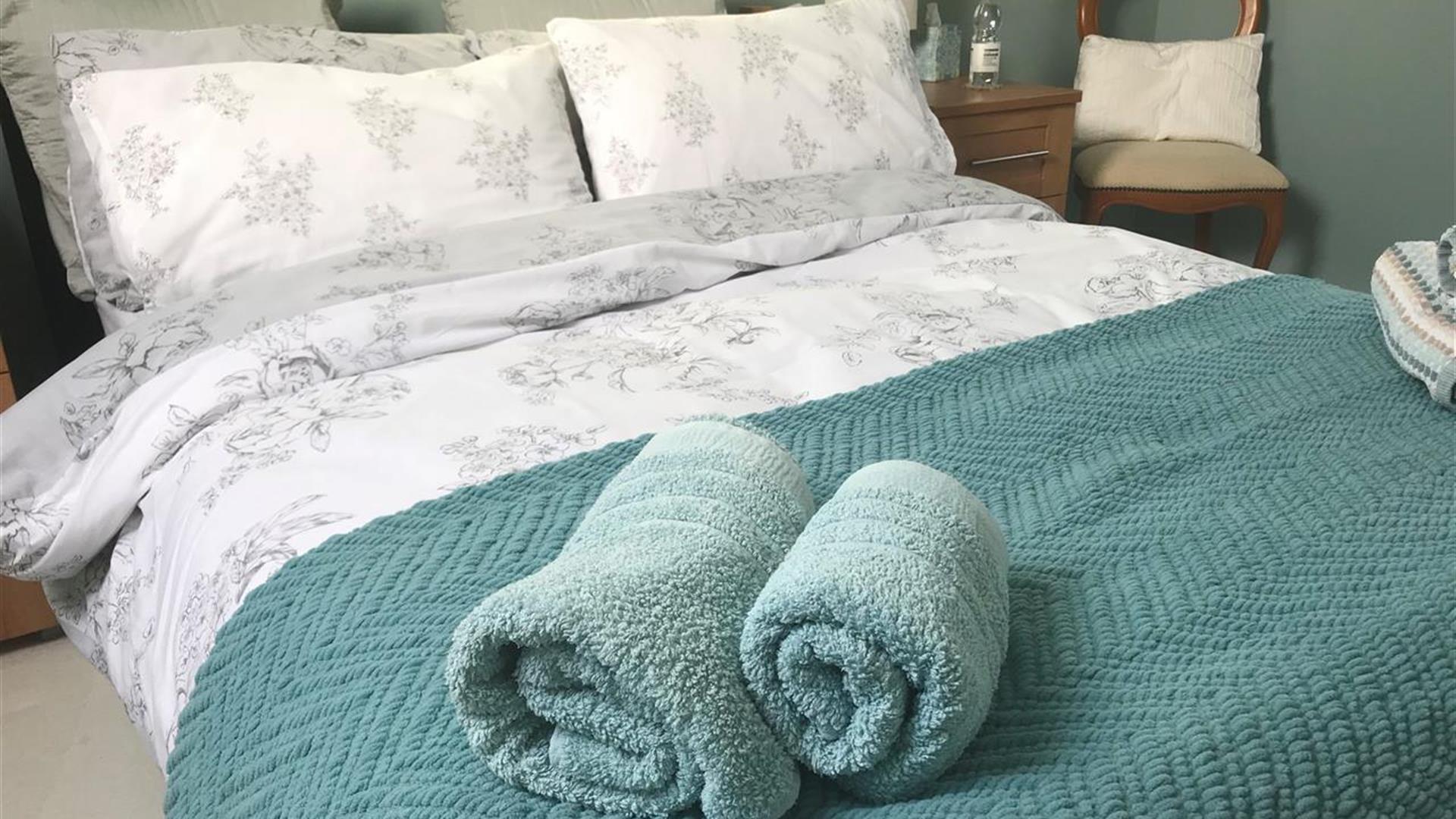 Image shows double bed with rolled up towels at the bottom