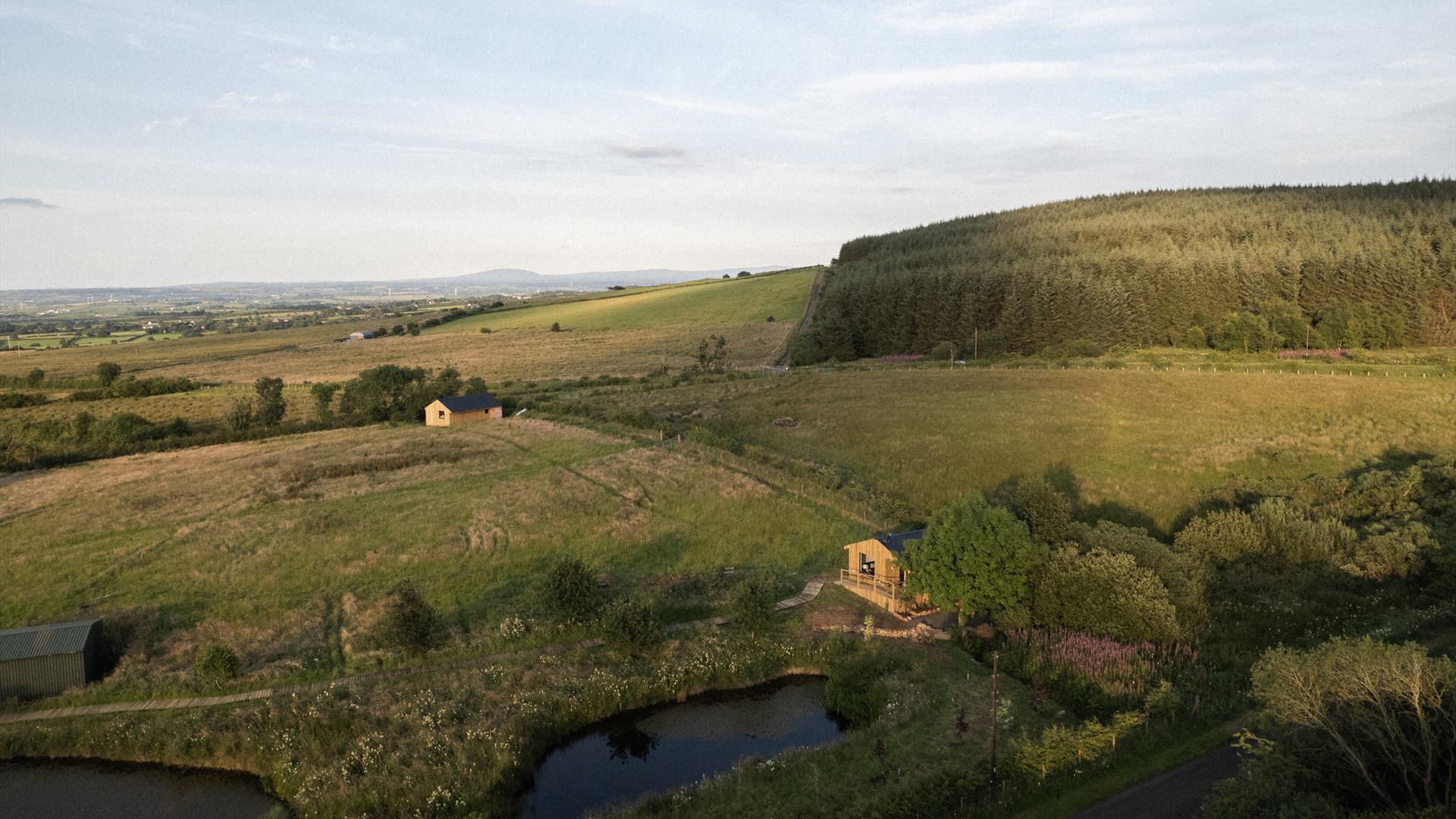Aerial image of The Bothans - two cabins and a lake on a forest edge.