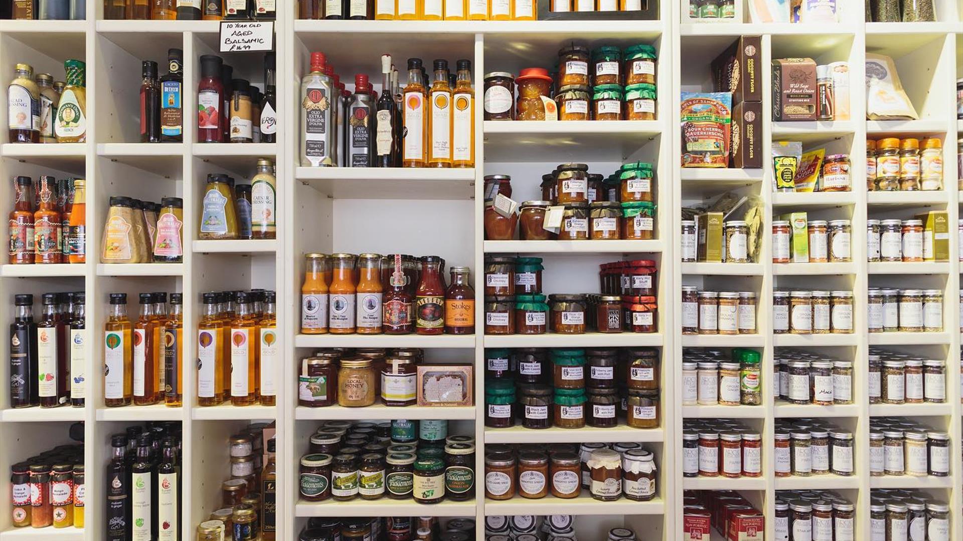 A wall covered with shelves of sauces, spreads and other food products.
