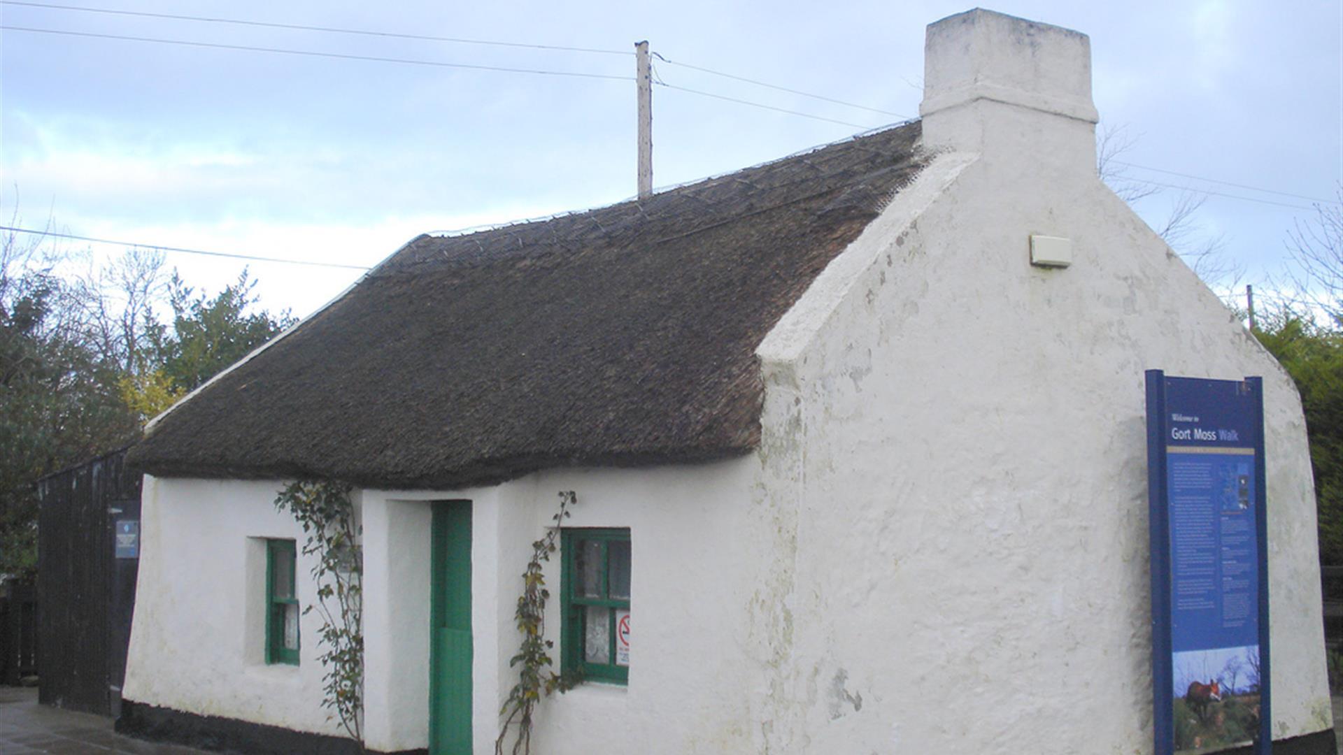 Image of a white cottage with a thatched rood and green door