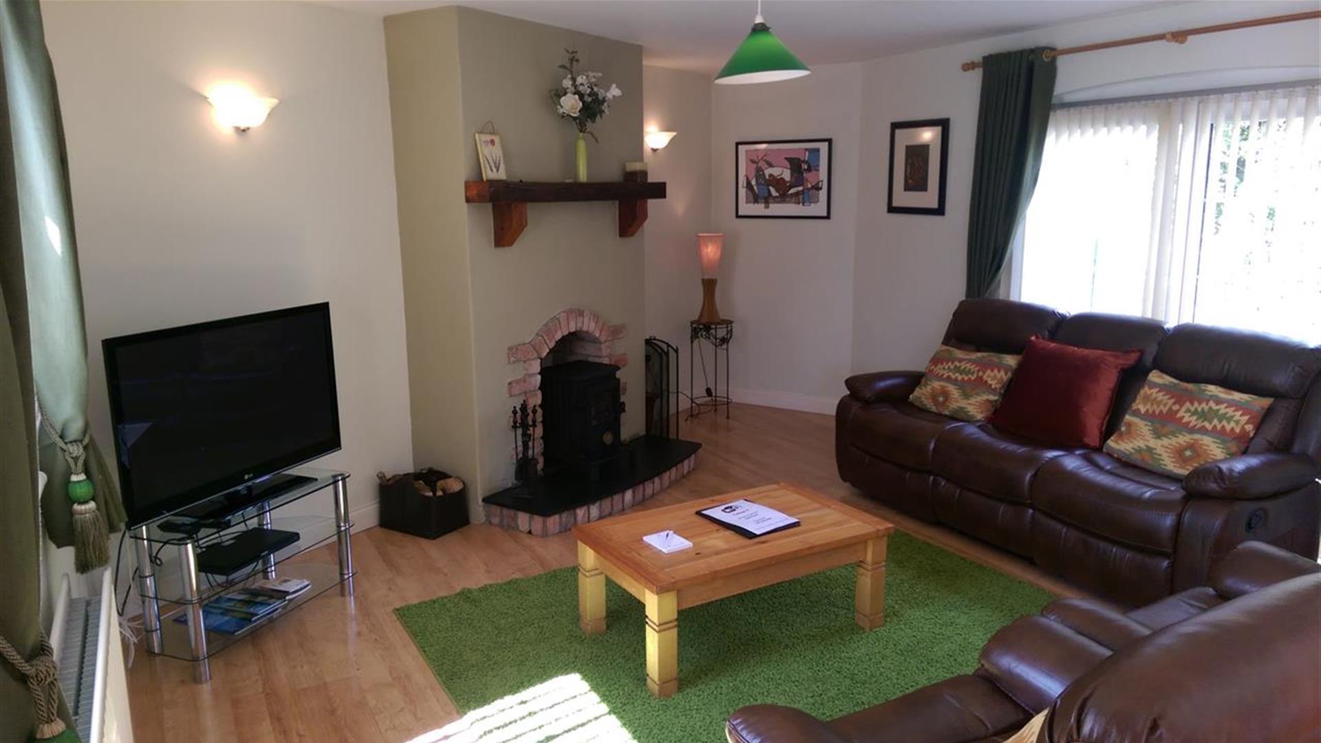 Image shows lounge area with leather sofas, fireplace, coffee table and TV