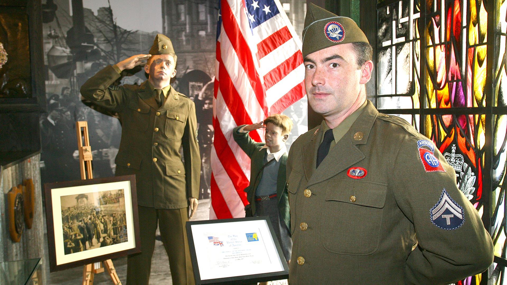 A man dressed up in a uniform from the Second World War standing in the gallery of the Northern Ireland War Memorial.