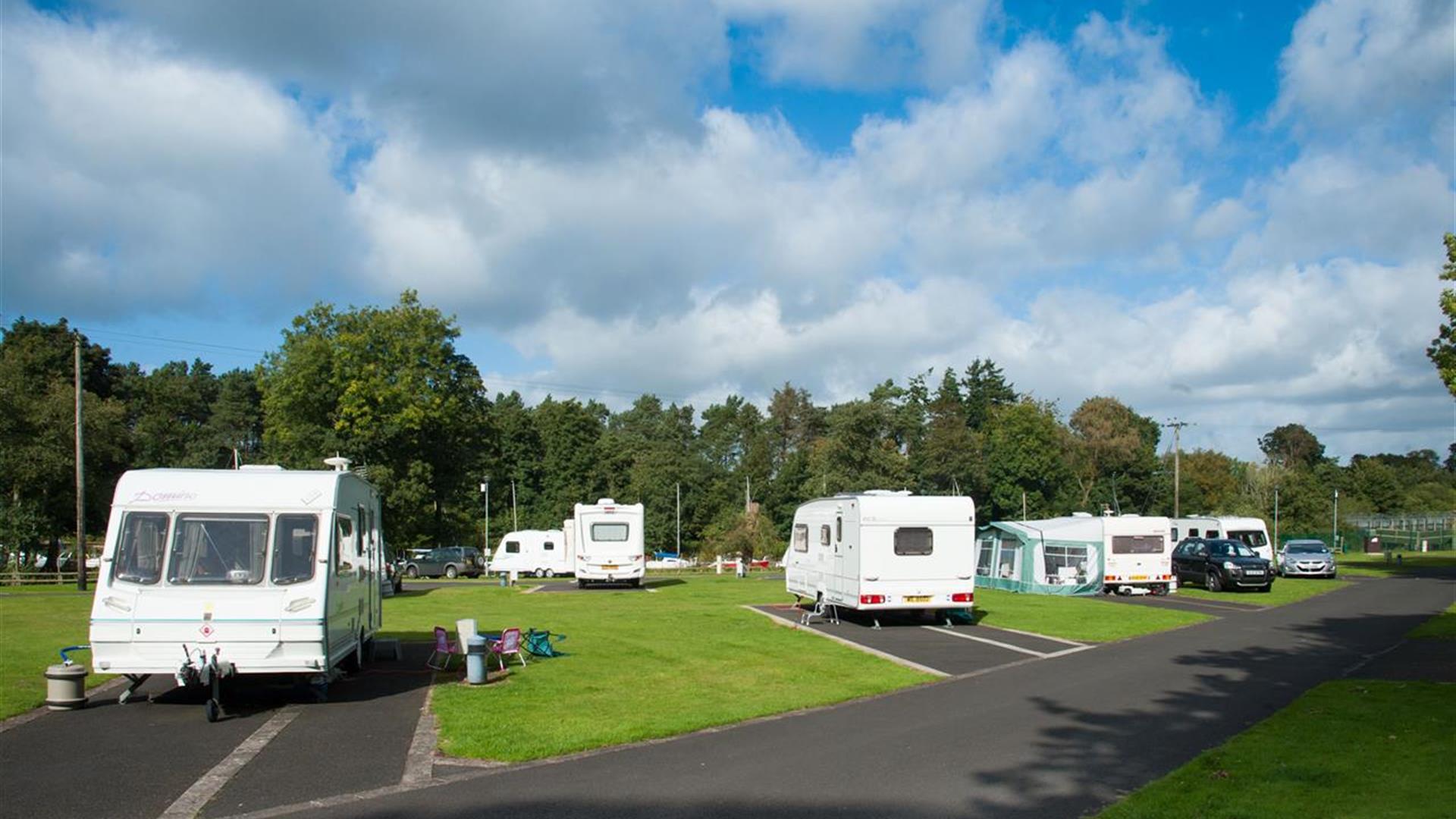 Caravans and cars parked in lots in a grassy area.