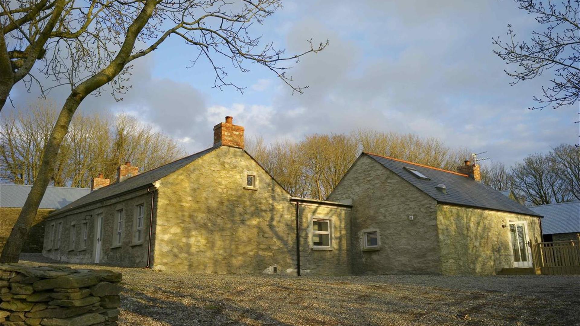 A corner view of a stone cottage with two sections.