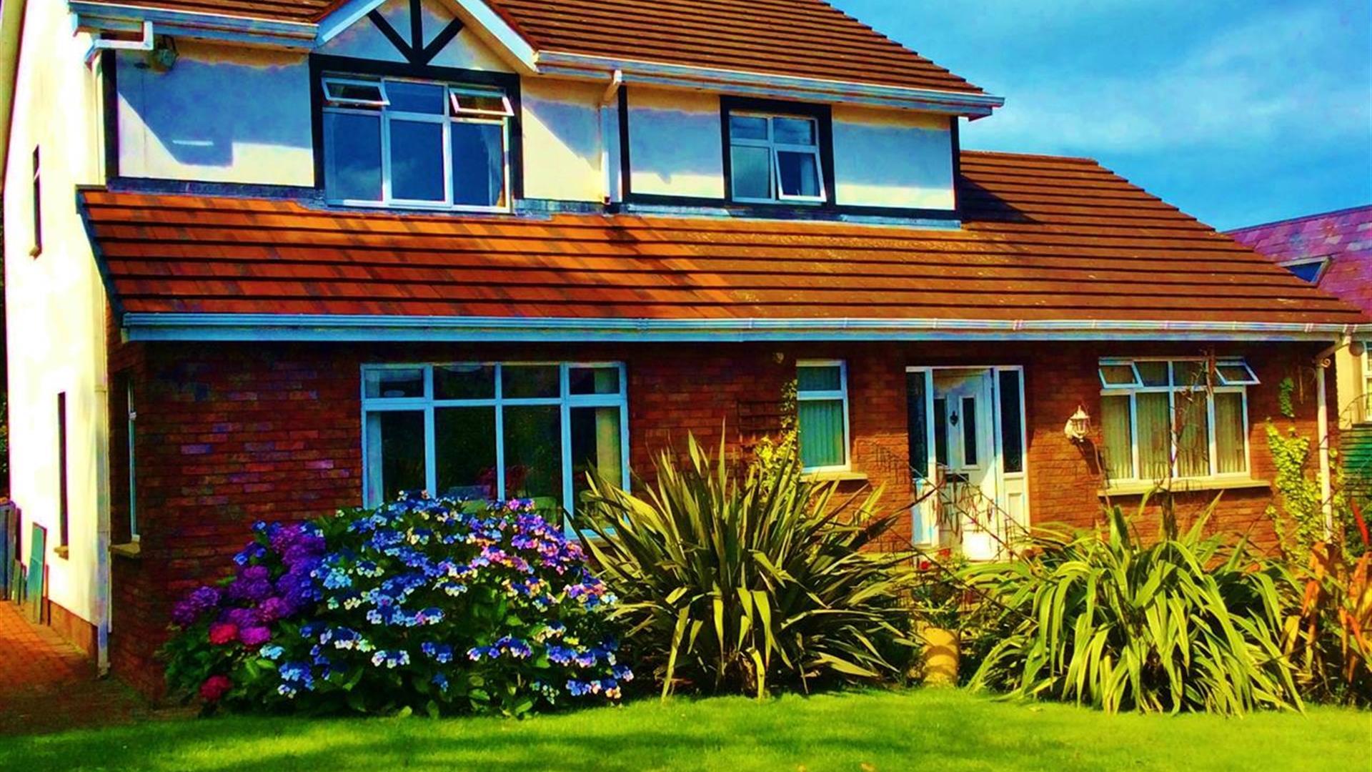 A two-story lodge with a garden of plants and flowers.