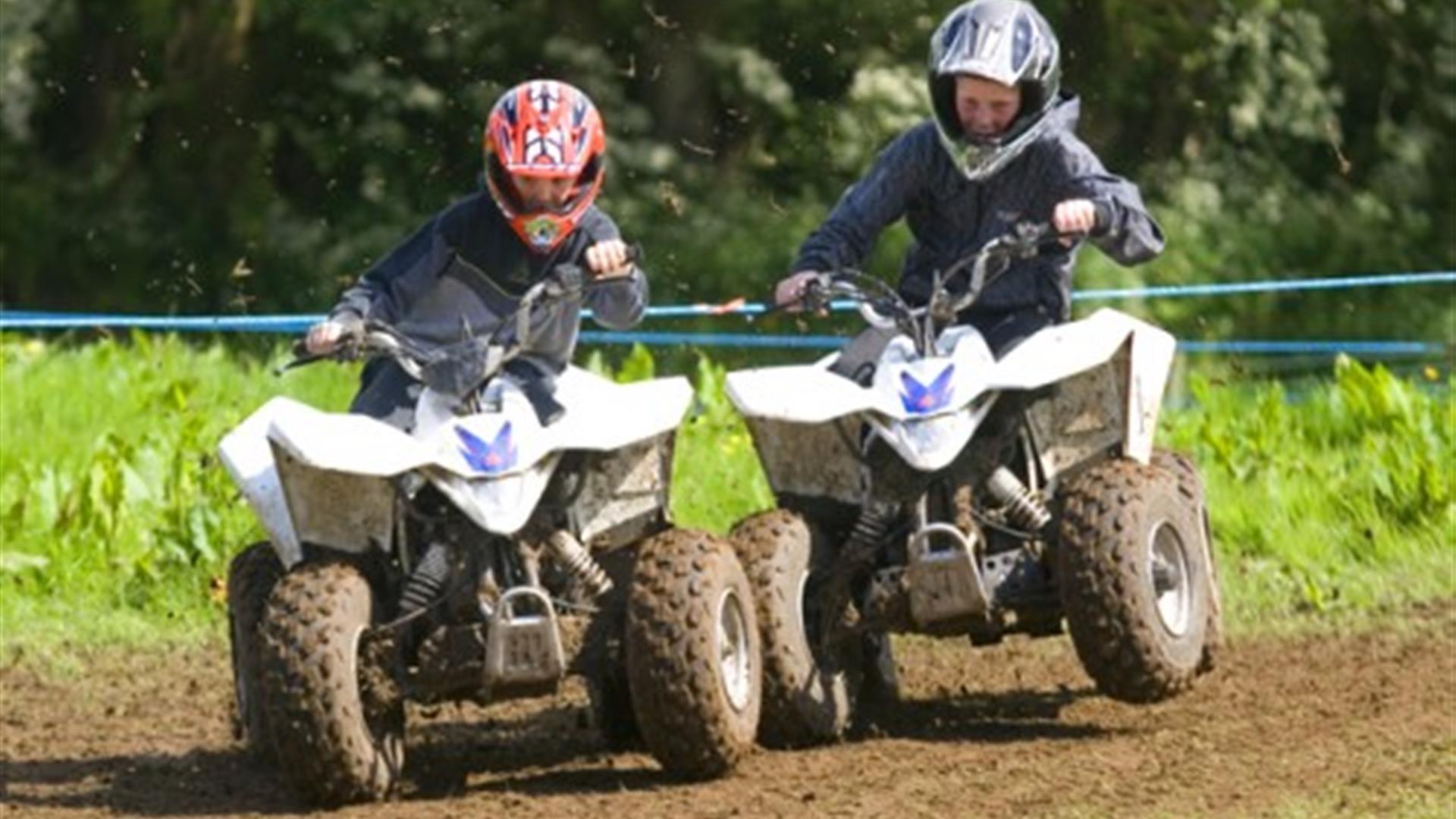 Image is of 2 children on mini quad bikes