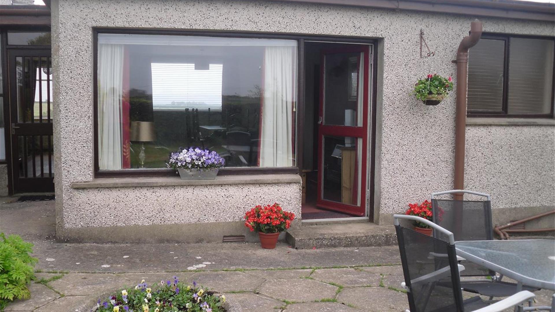 Photo of entrance to accommodation and seating area in yard