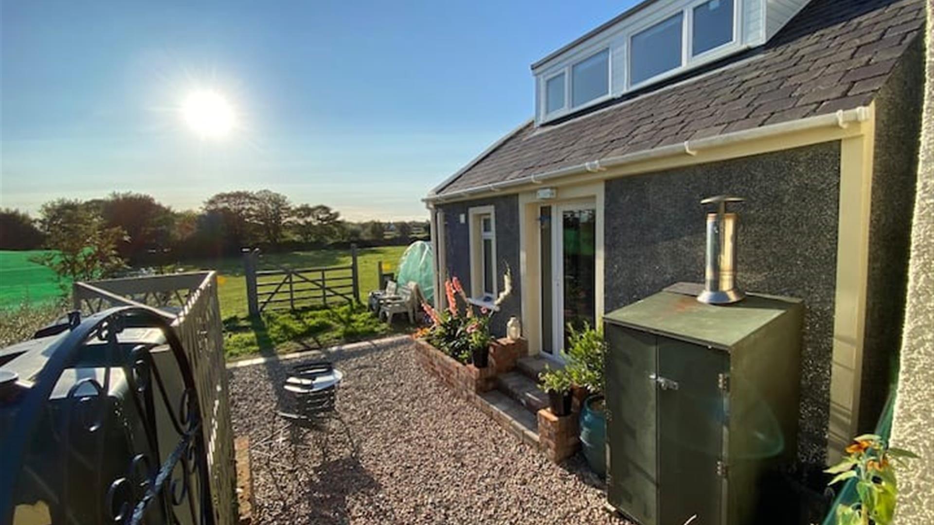 Photo of outside of the accommodation with fields, blue sky and sunshine