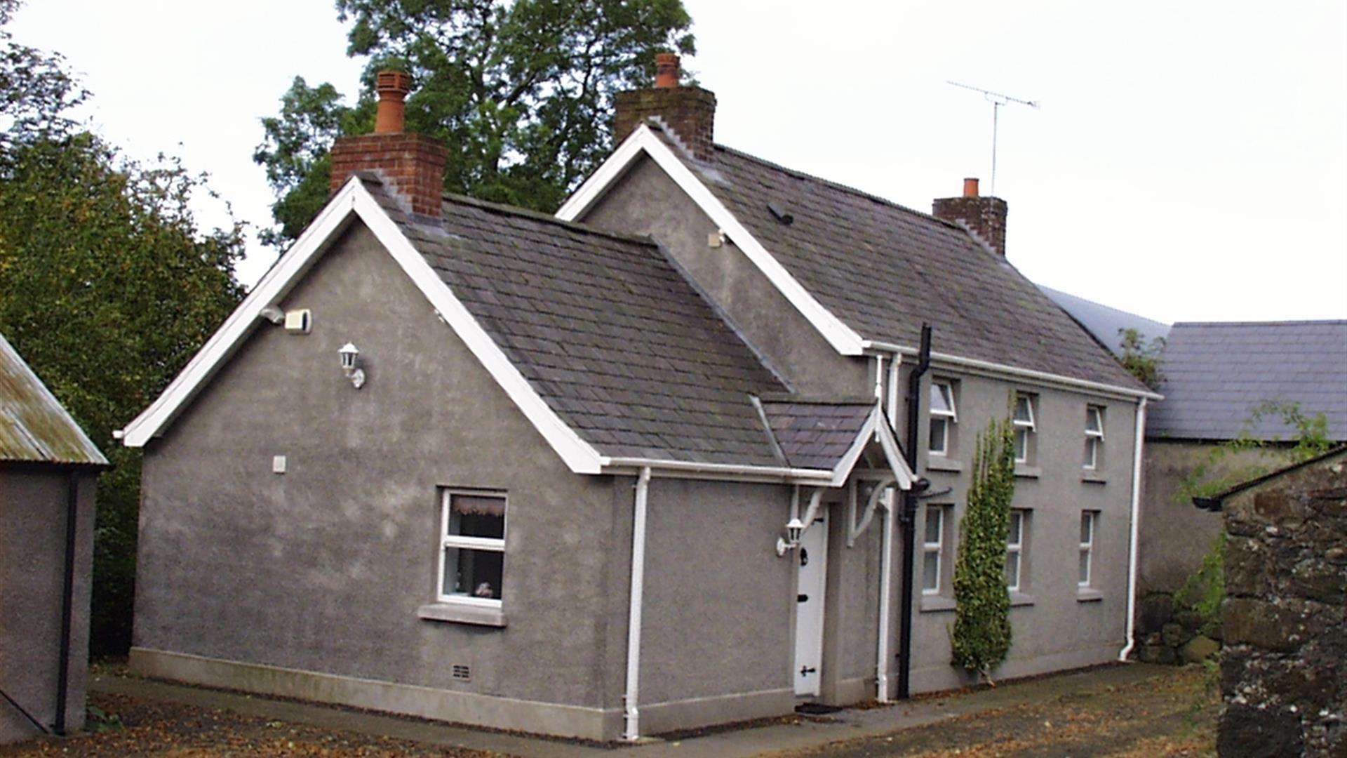 A side angle view of the front of a large grey house.