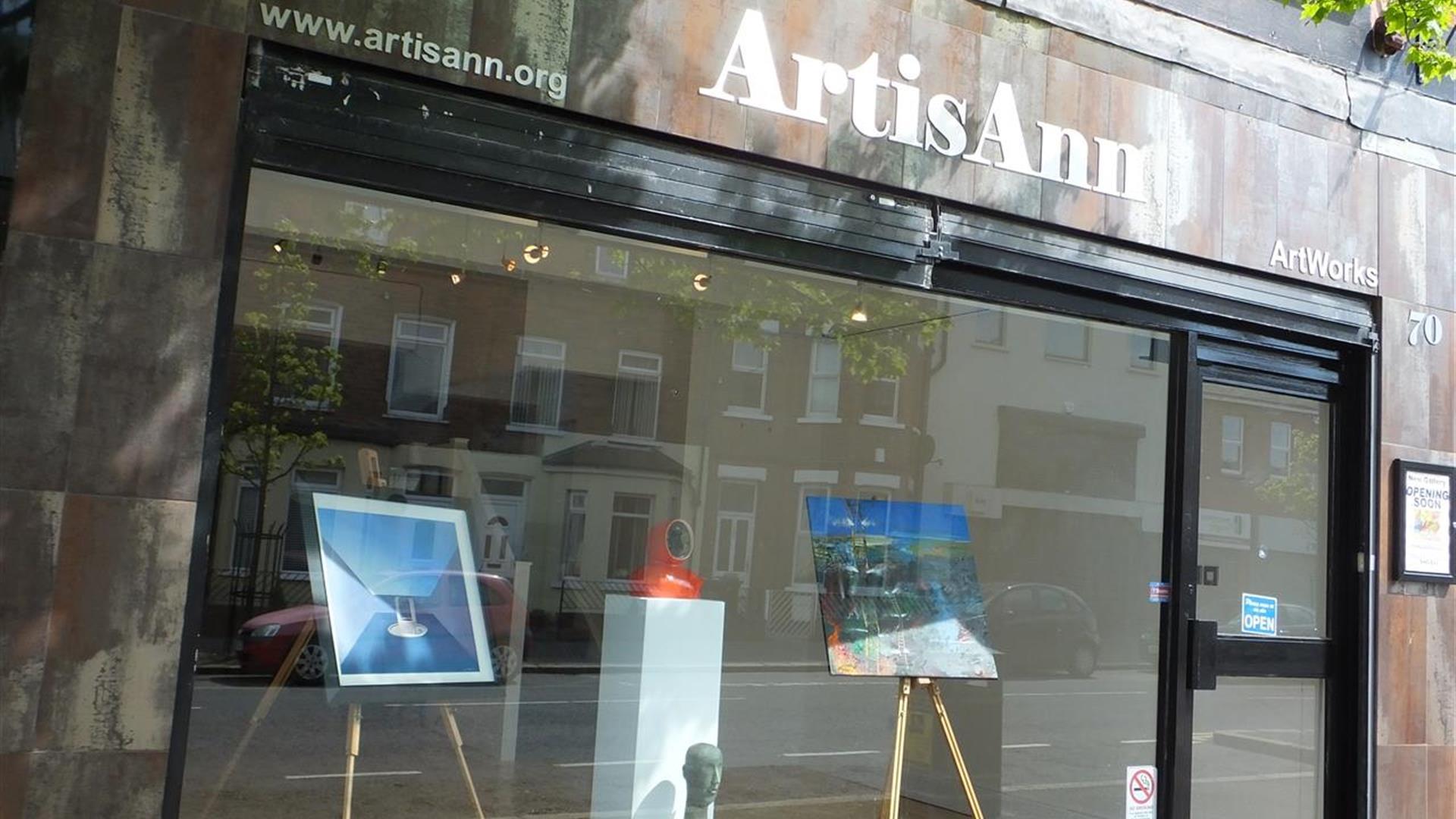 The front exterior of an art gallery with art displayed through a glass front.