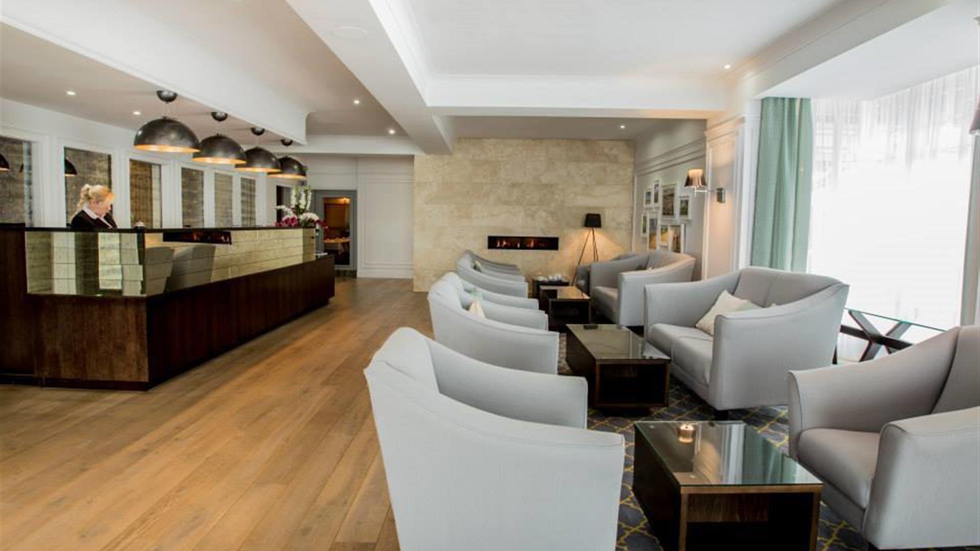 Image shows receptionist at desk in reception area. Also chairs and coffee tables