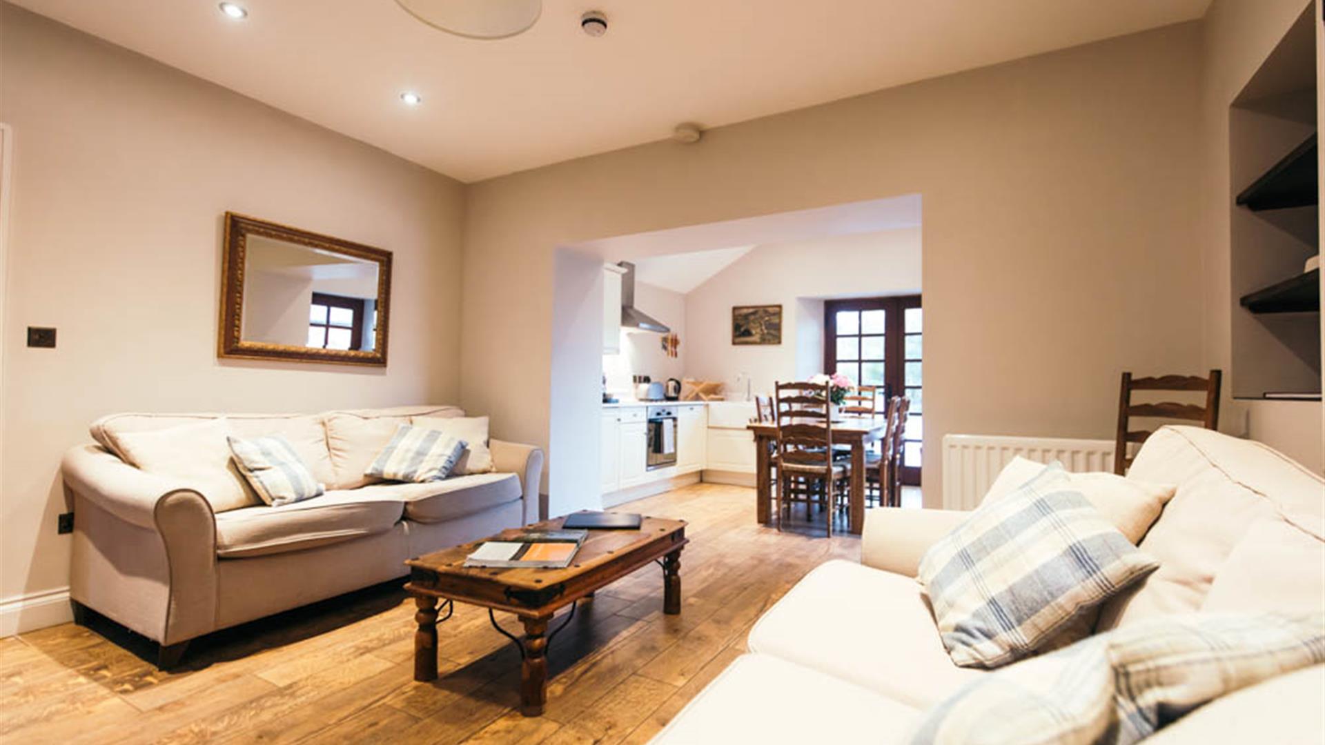 Image shows lounge area with 2 sofas, coffee table and wooden floor