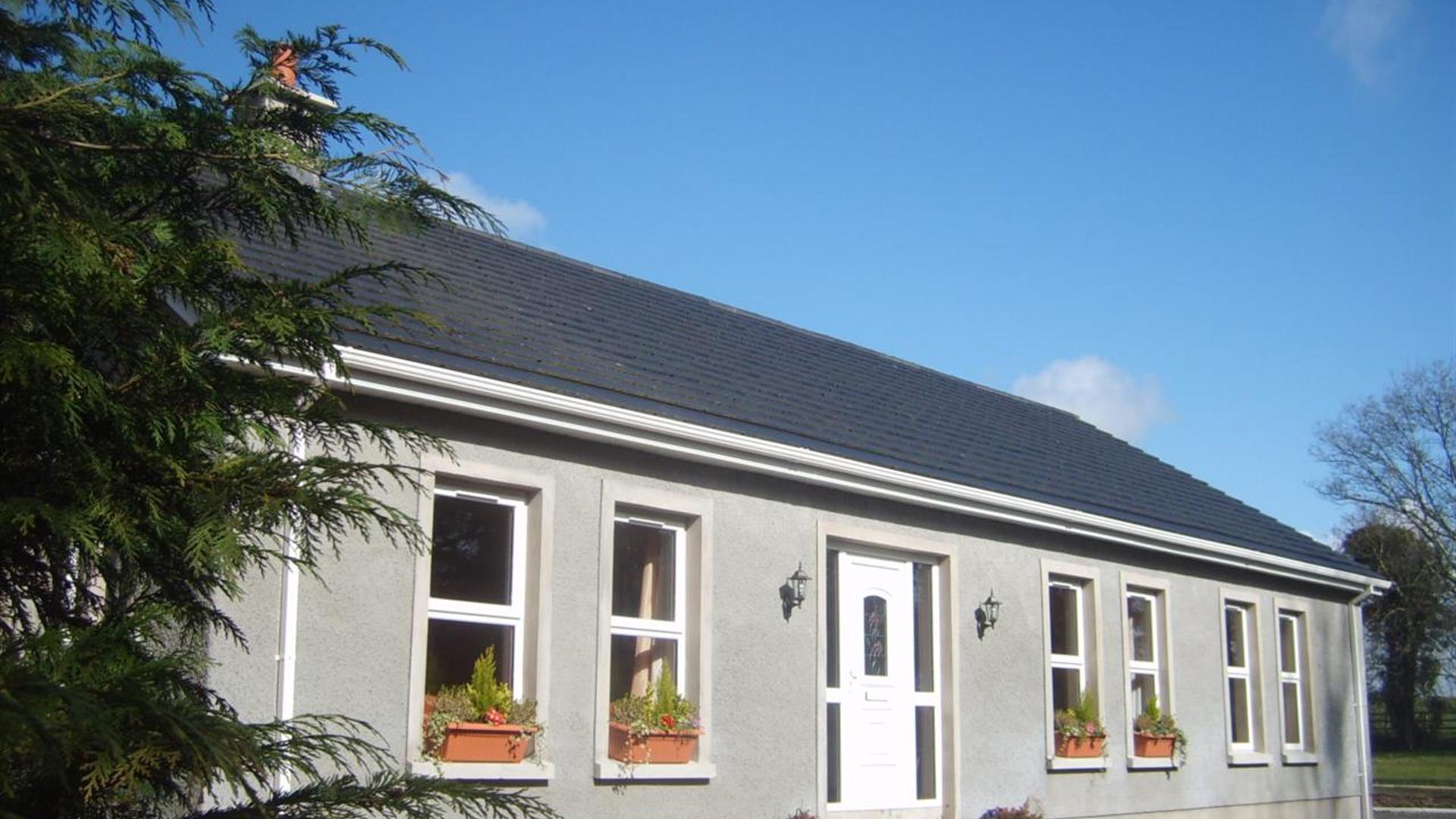A single-story lodge with a tree and plant pots on the window ledges.
