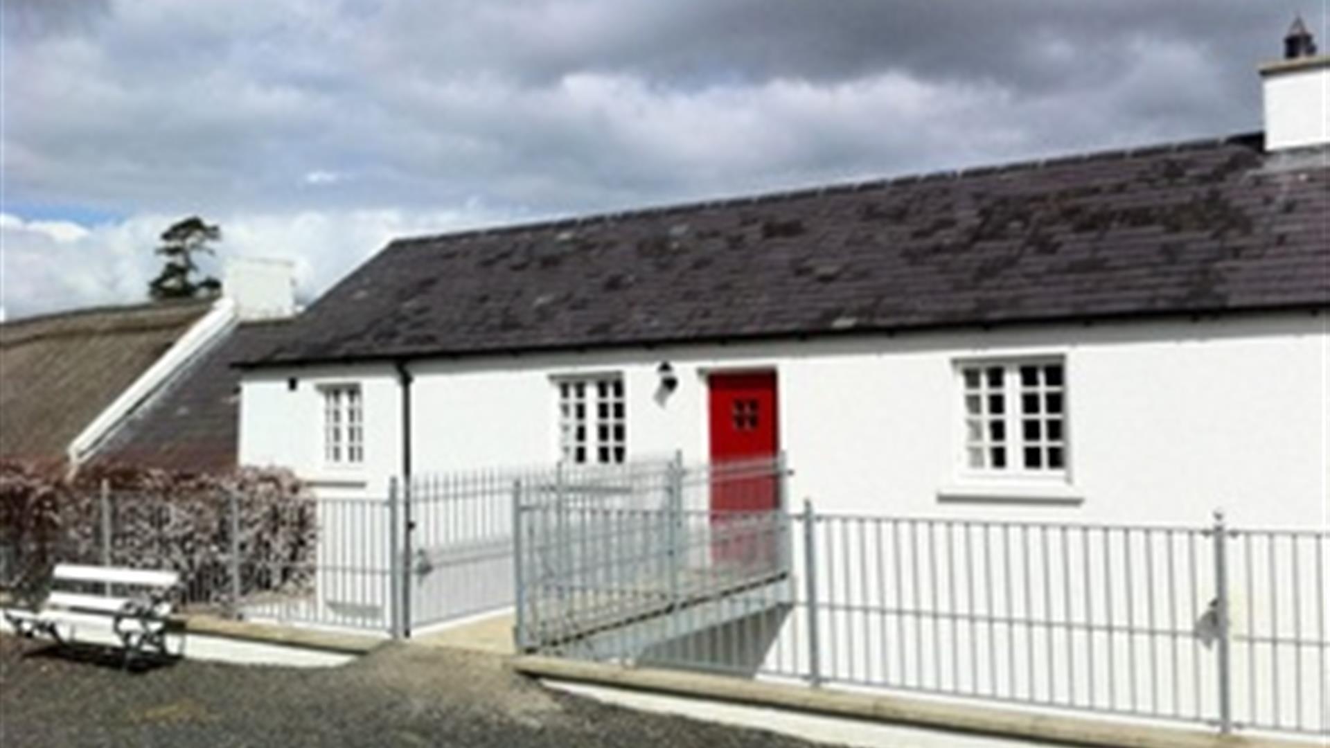 Outside of cottage with white exterior and red door