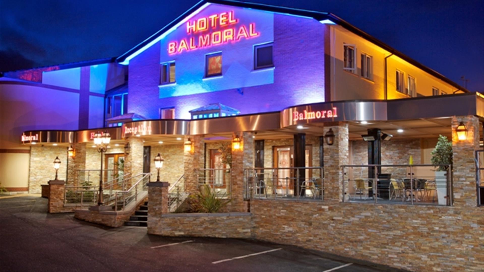 A photo of a hotel with an outdoor seating area lit up at night.