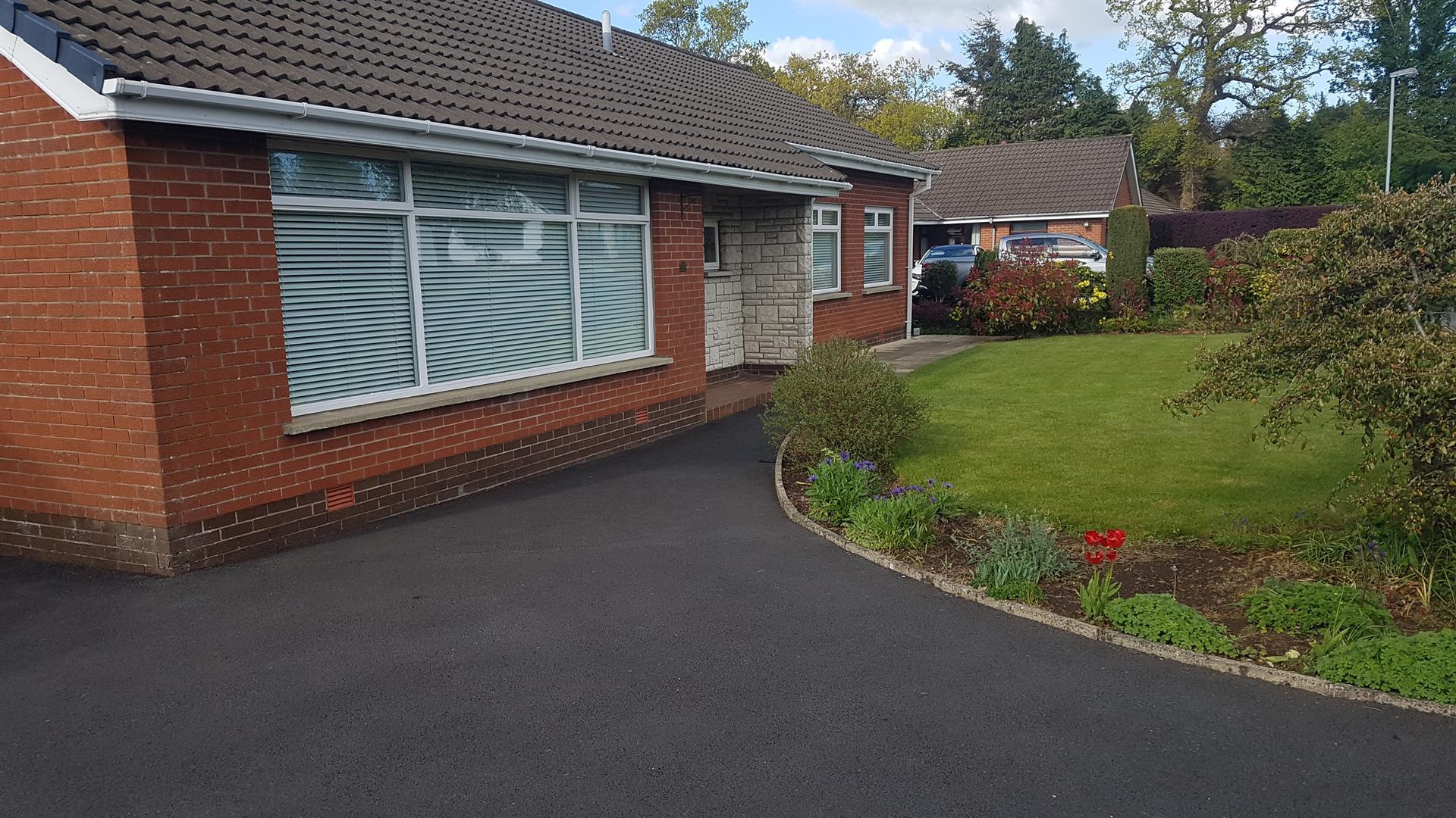 Driveway leading to a bungalow with a well-kept front lawn.