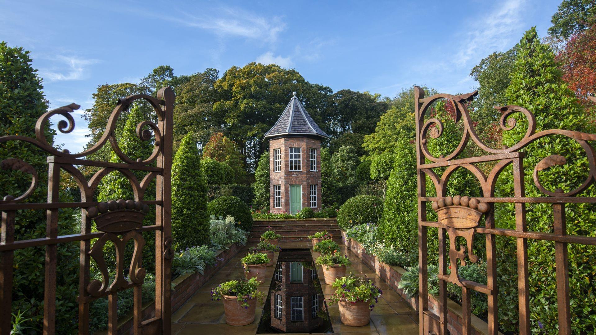 Historic Antrim Castle Gardens with formal landscaping, mature trees, and part of the Clotworthy Arts Centre building visible.