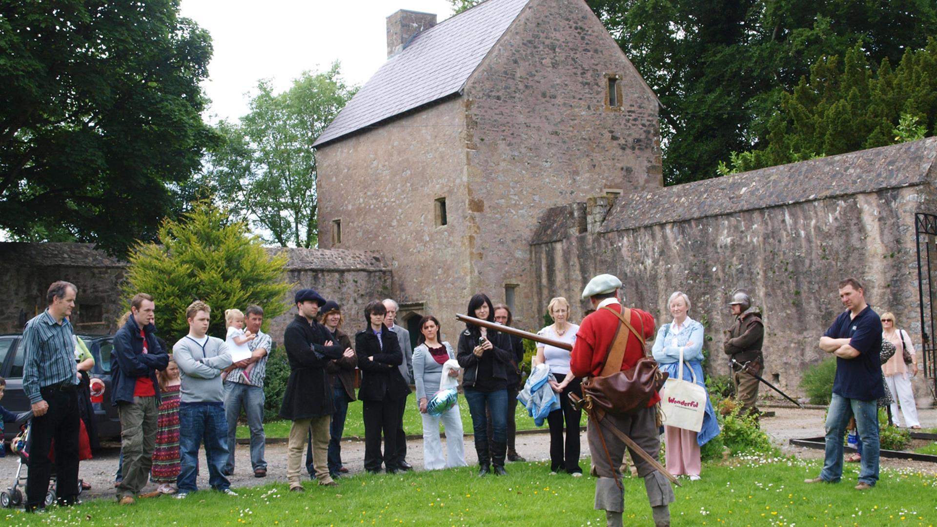 Group of people listening to a man in costume in front of Benburb castle