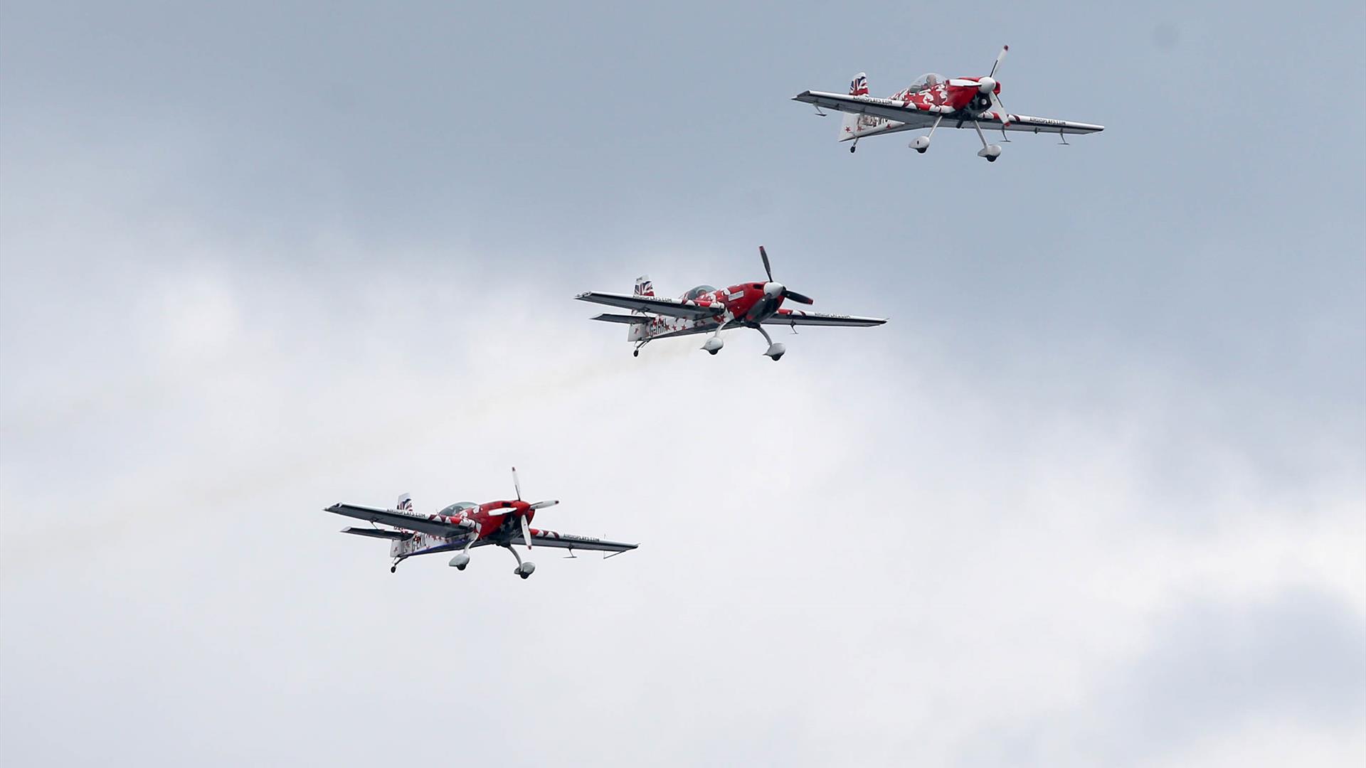 three red and white planes flying together through the sky