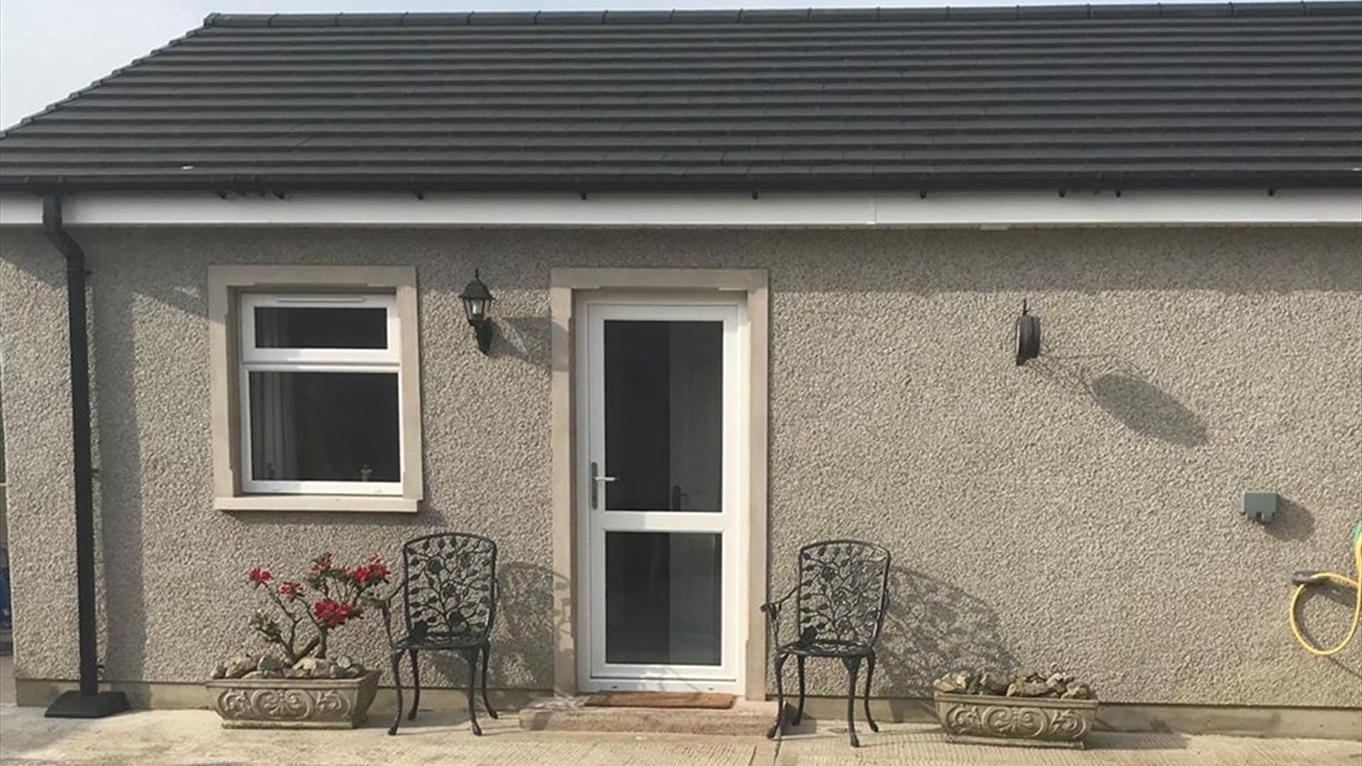 Image is of front of the property with wrought iron chairs at either side of the front door