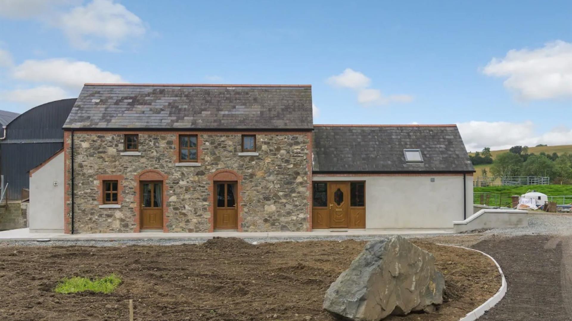 Image shows front of stone built property plus extension