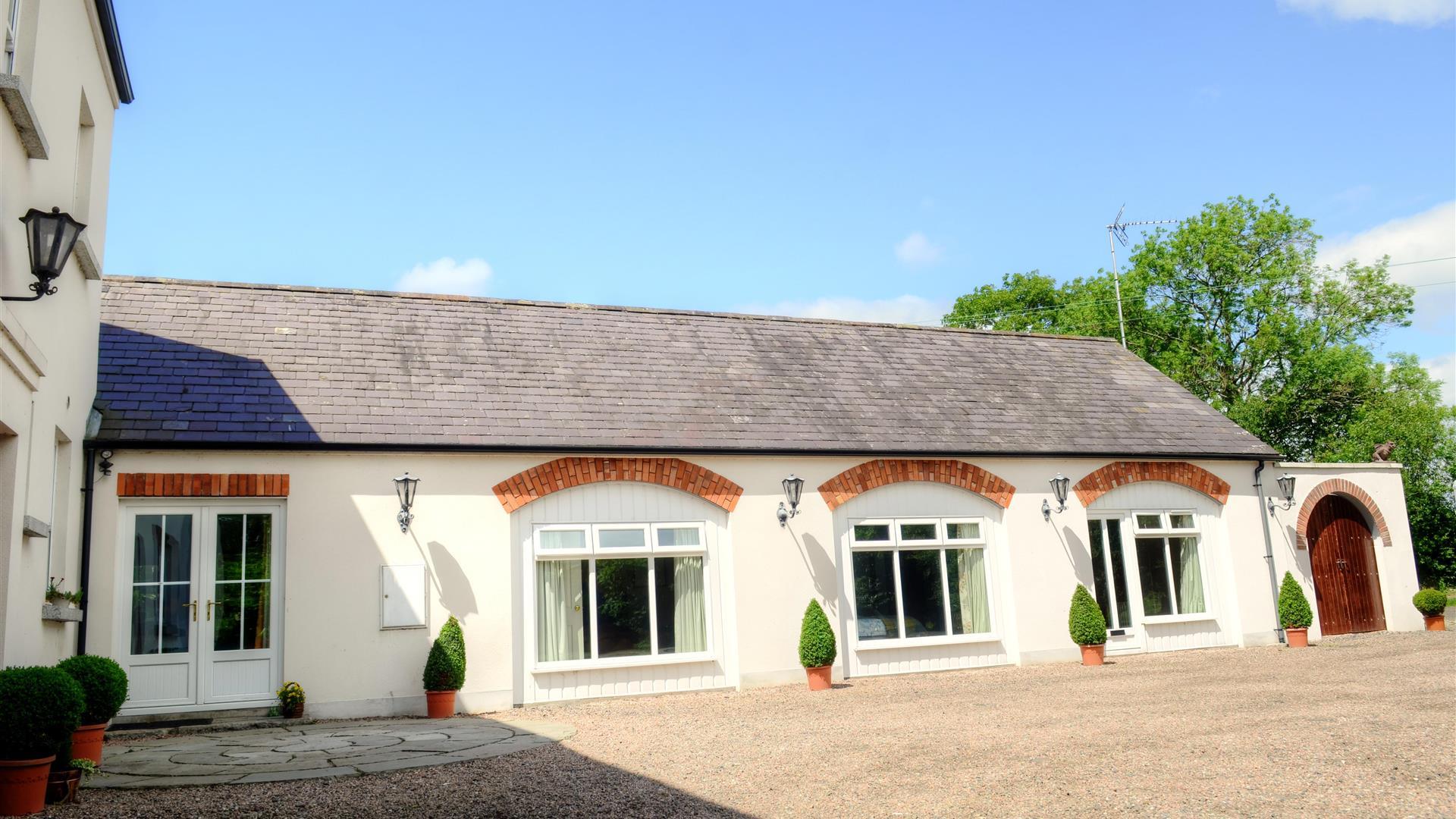 Image shows front of the property facing onto gravel drive/courtyard