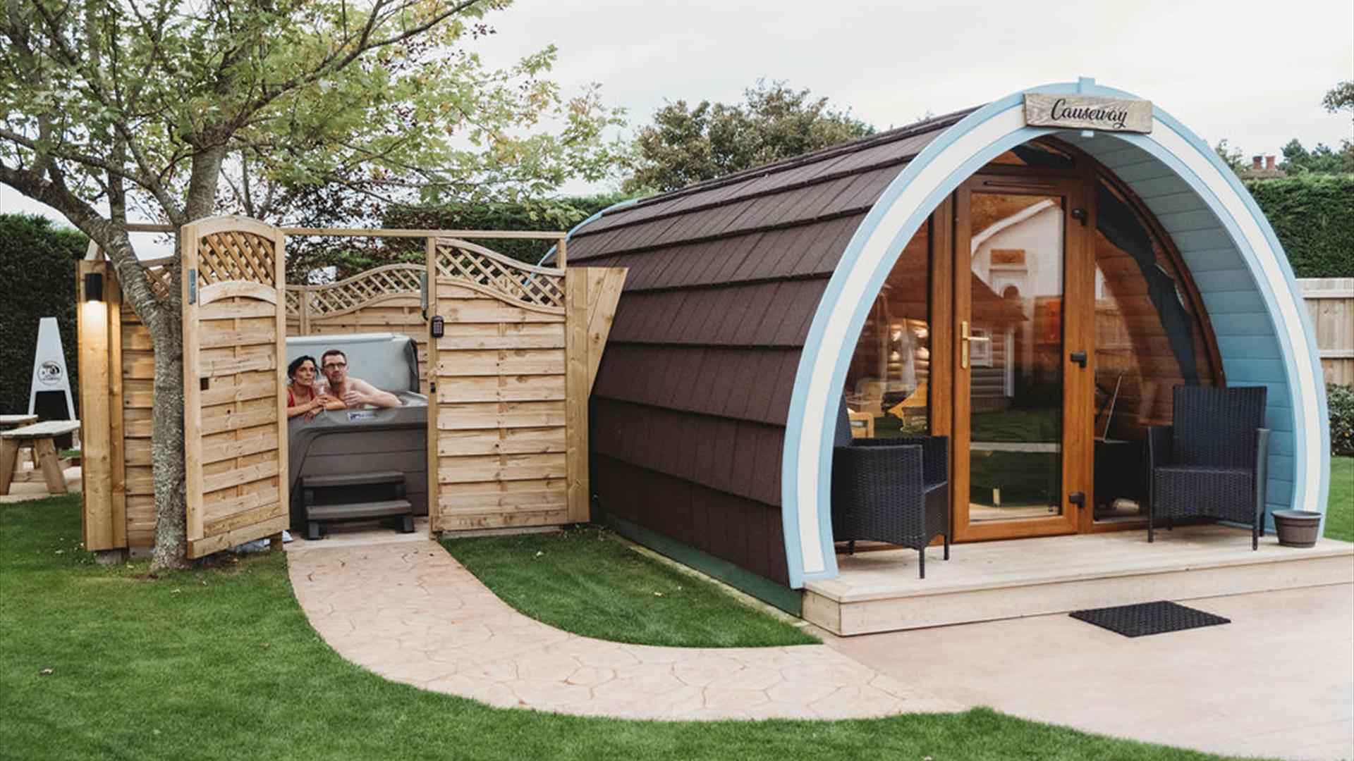 Glamping pod with hot tub beside enclosed with open gate