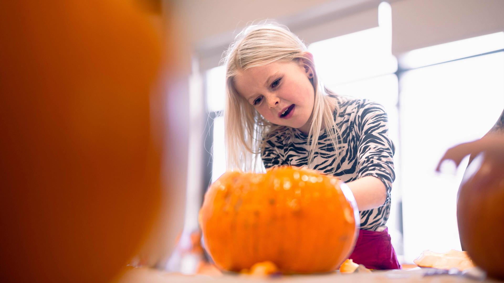 child carving pumpkin