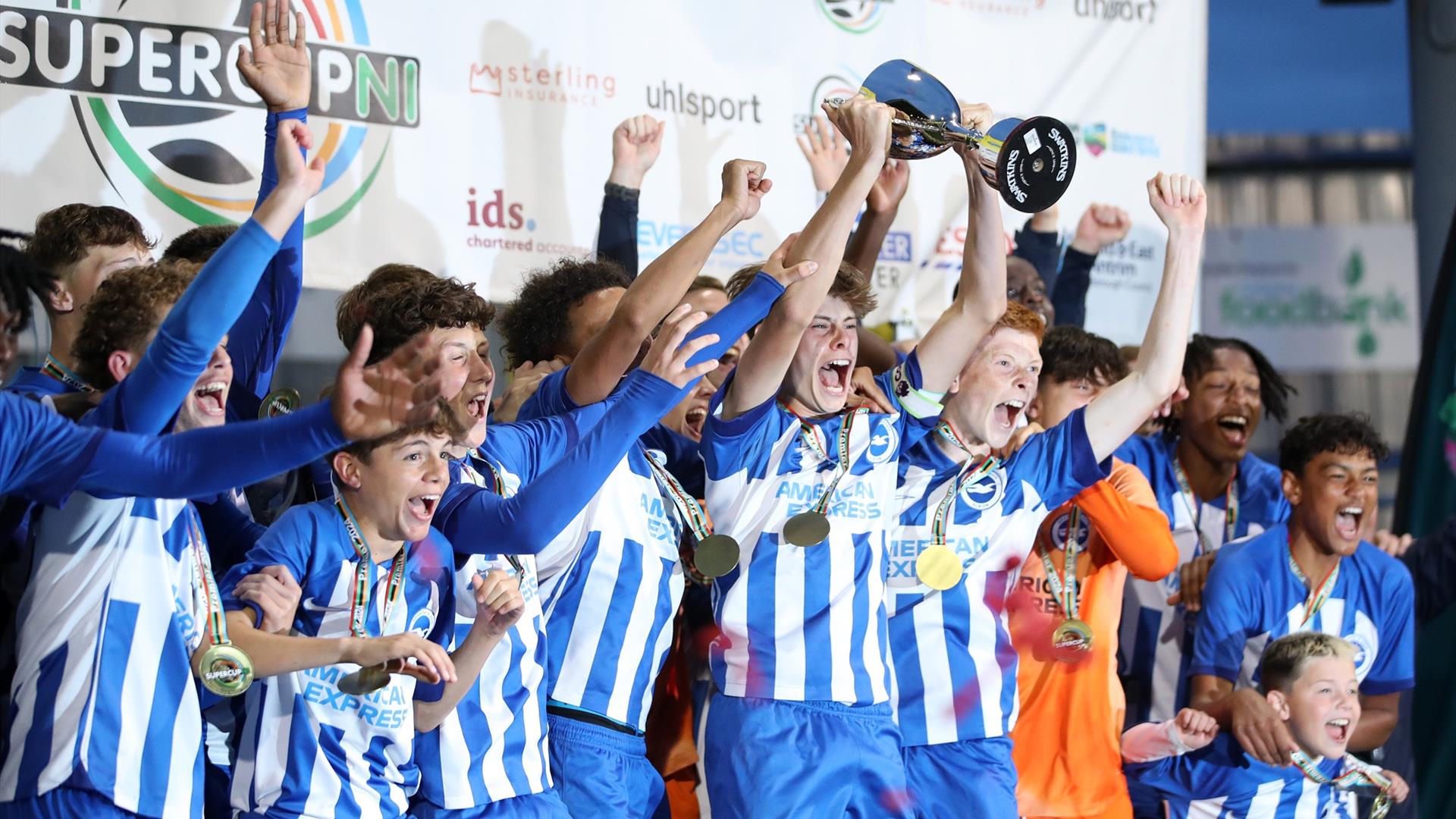 a male youth football team celebrates winning a trophy