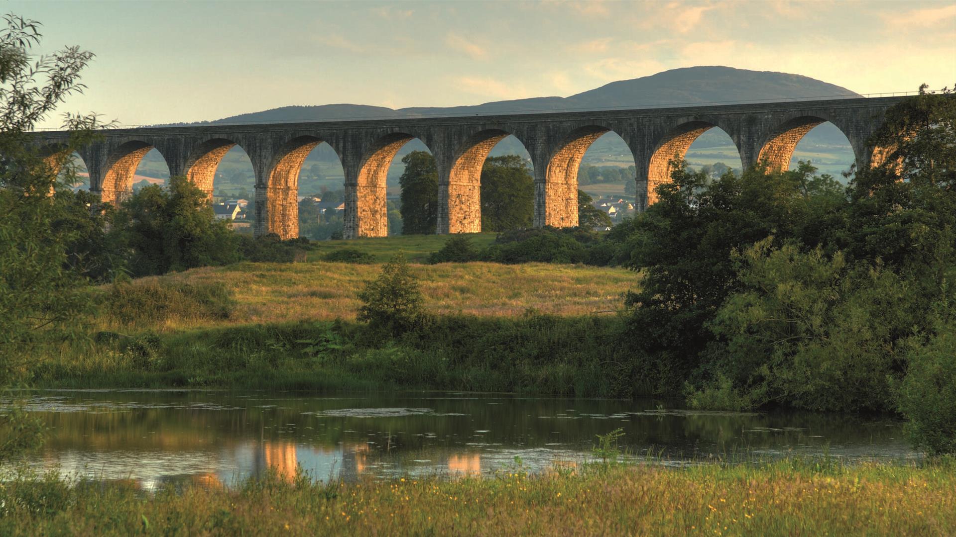 View of the Craigmore Viaduct near Newry, a large stone railway bridge with 18 arches spanning a valley, with a train crossing its top.