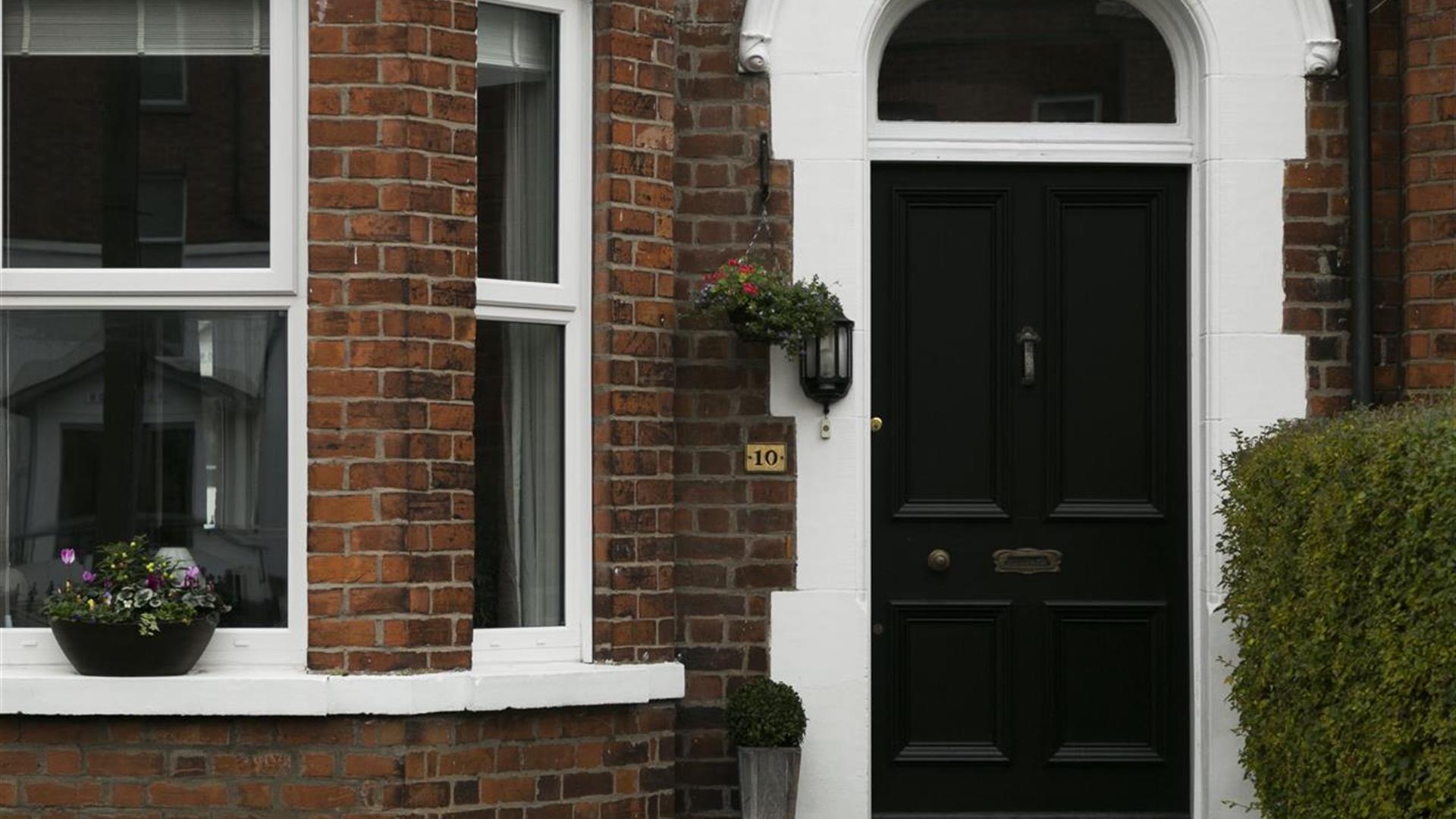 A black front door with a front window decorated with plants.