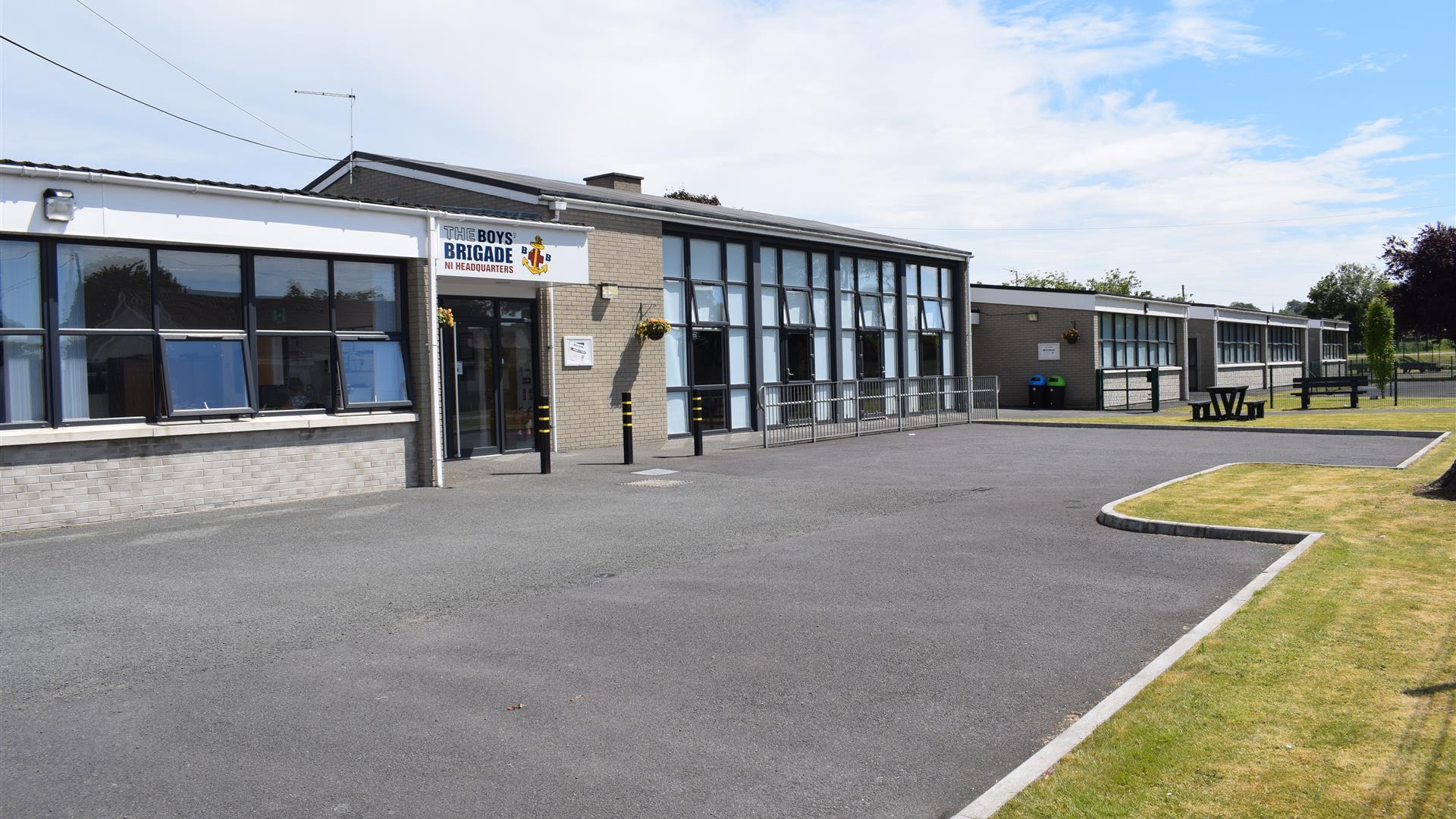 Image is of front of the building with tarmac driveway and grass area beyond