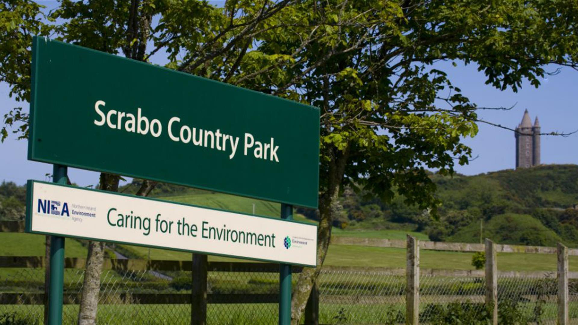 Image of the NIEA signpost entitled Scrabo County Park, caring for the environment with Scrabo Tower in background